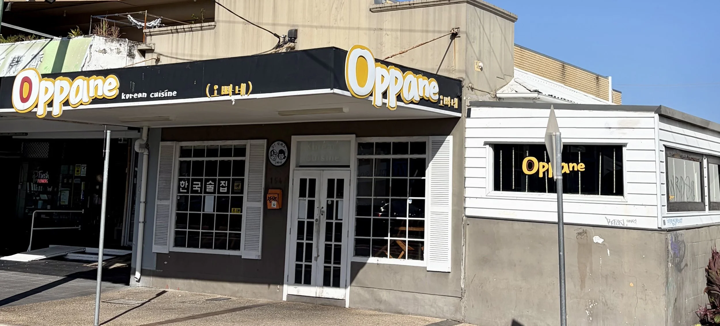Street view showing character white window frames and the restaurant logo in the colours white, yellow and black.