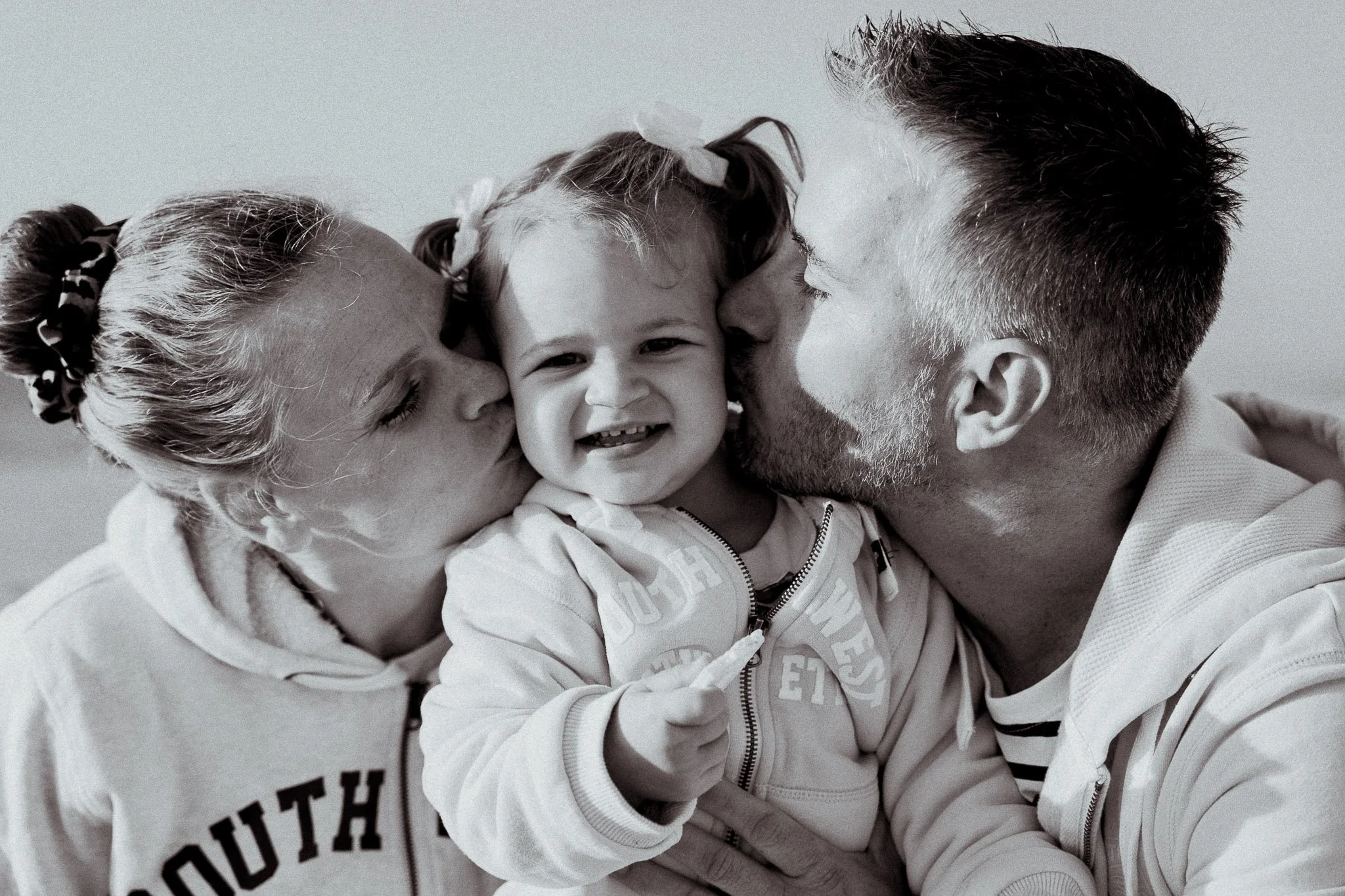 photographe-famille-seignosse-bisous-parents-fillette-noir-et-blanc.jpg