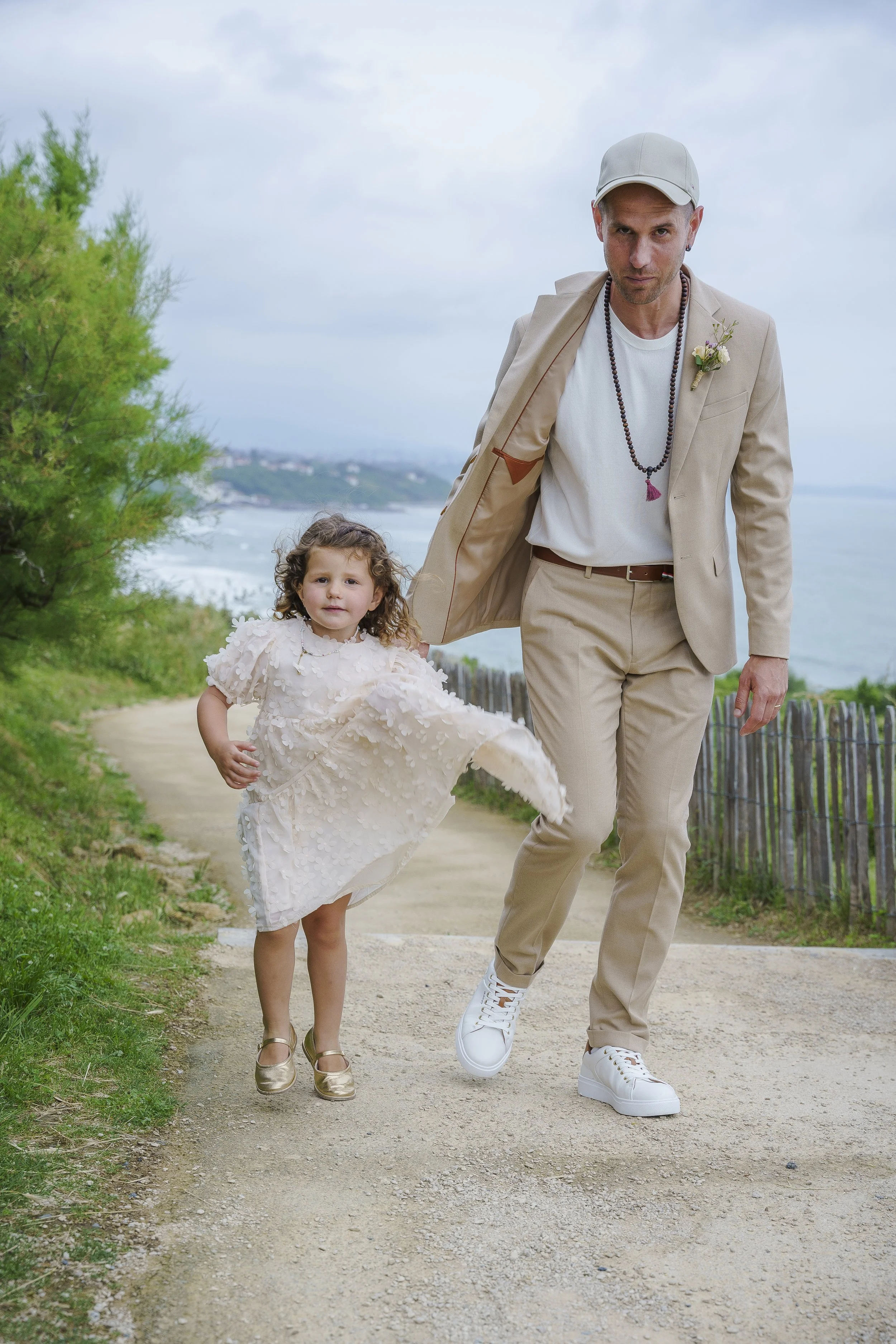 Un père et sa fille en habits de mariage marche le long de la corniche à Bidart