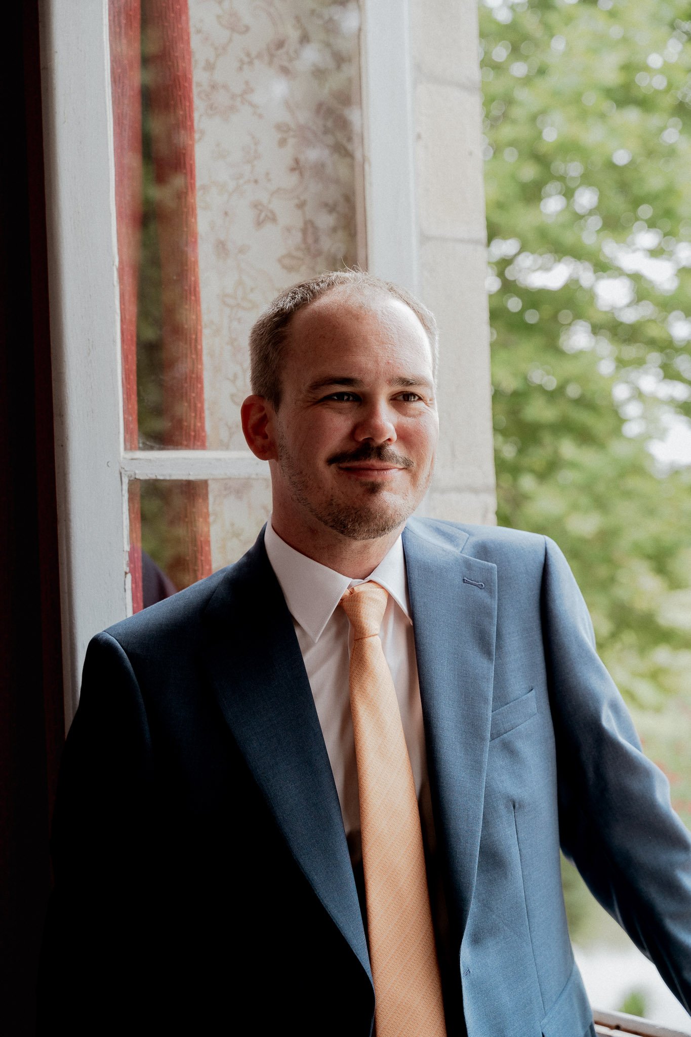 photographe-mariage-moliets-portrait-marie-costume-bleu-fenetre.jpg