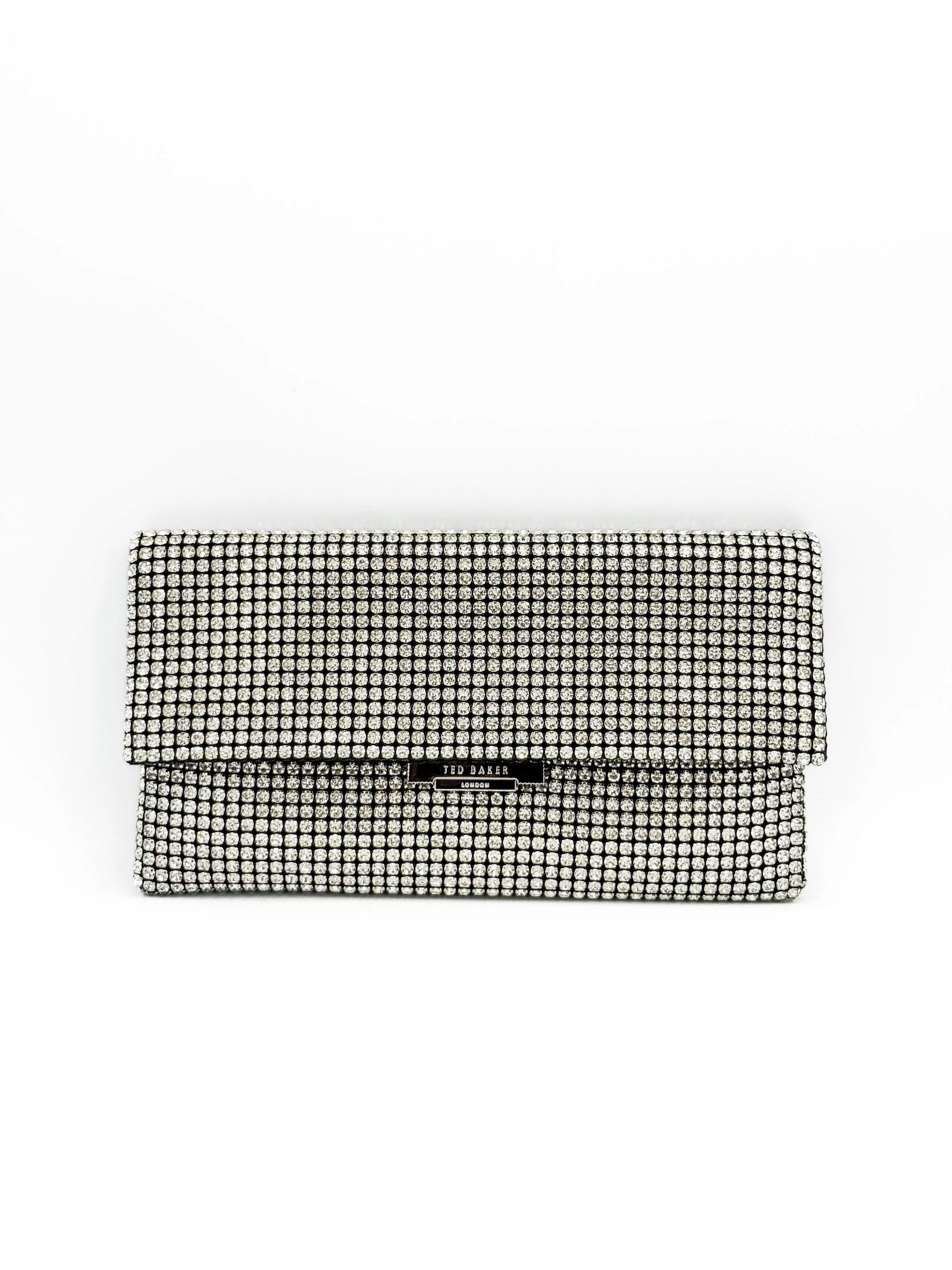 A silver clutch purse covered in rhinestones, with a Ted Baker London logo on the front.
