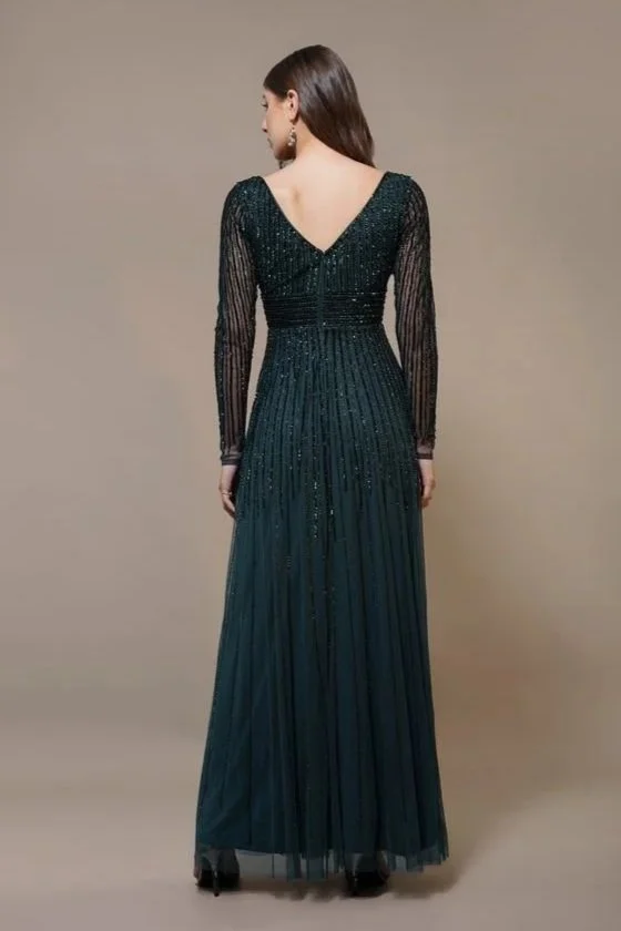 Back view of a woman wearing a long, dark green, sequined gown with sheer long sleeves and a V-shaped back.