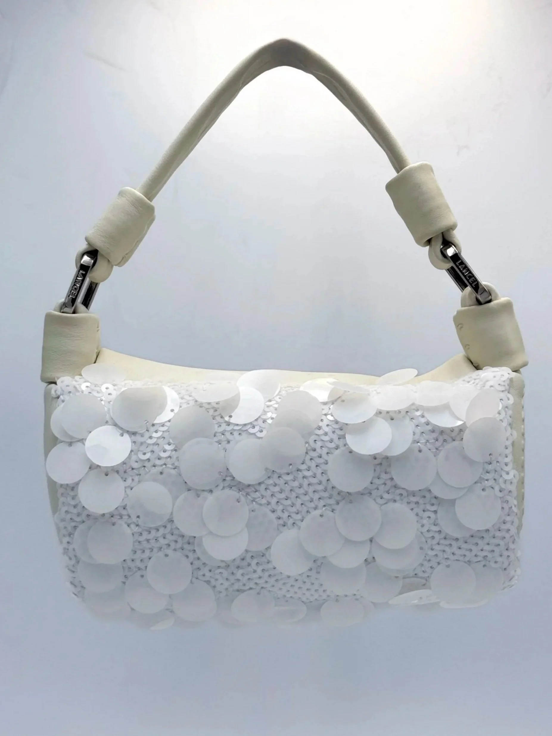 White handbag with a large handle, decorated with white sequins.