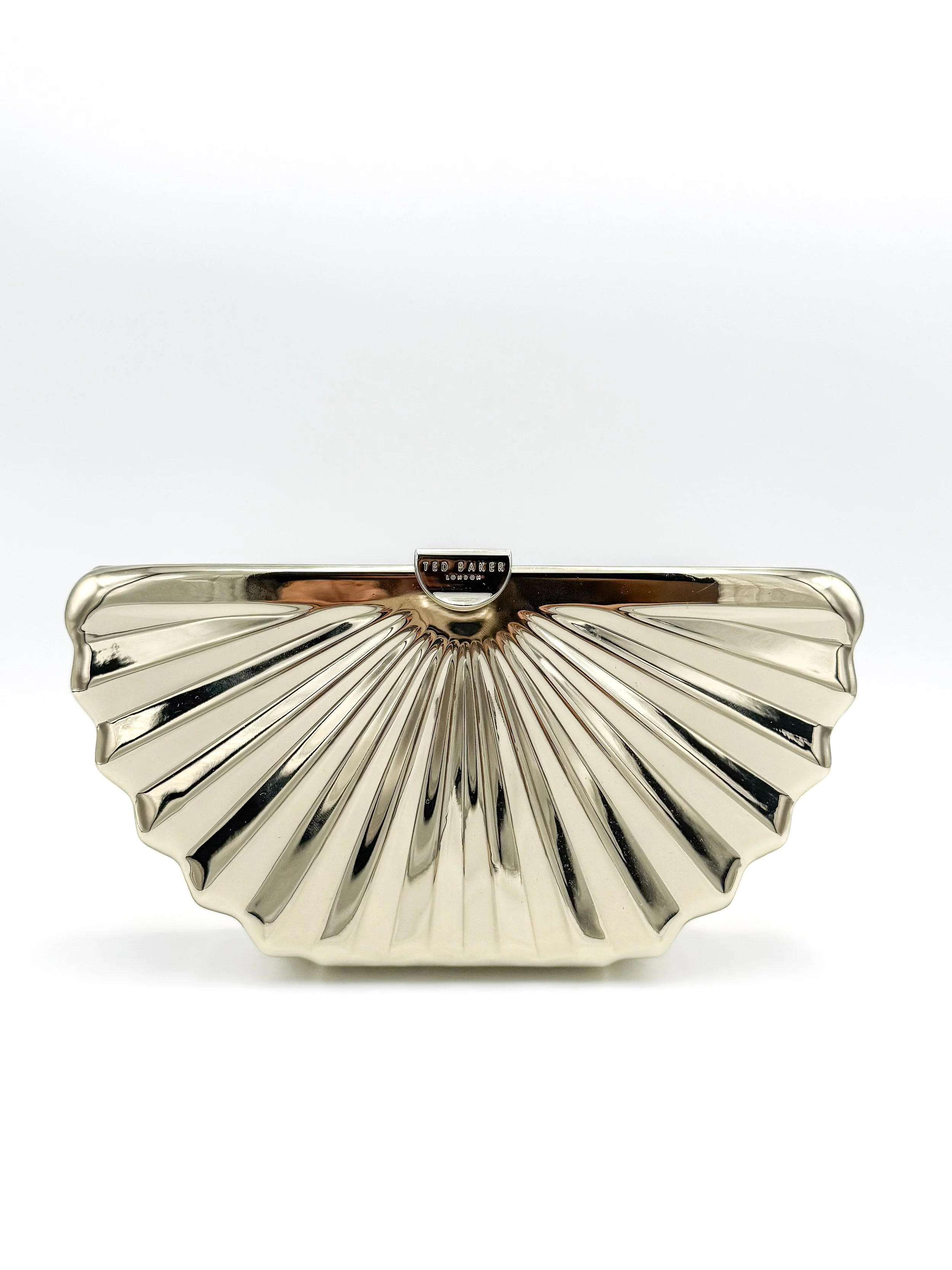 Gold-colored clutch purse with a fan-shaped, ridged design and a small logo plate at the top center reading 'Ted Baker London'.