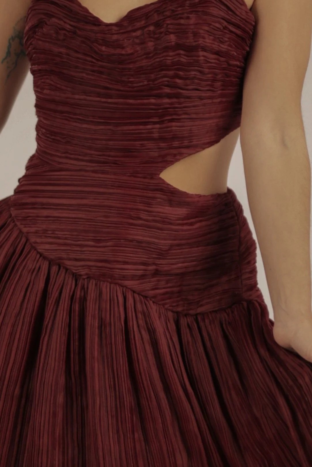 Close-up of a woman wearing a maroon dress with cut-outs.