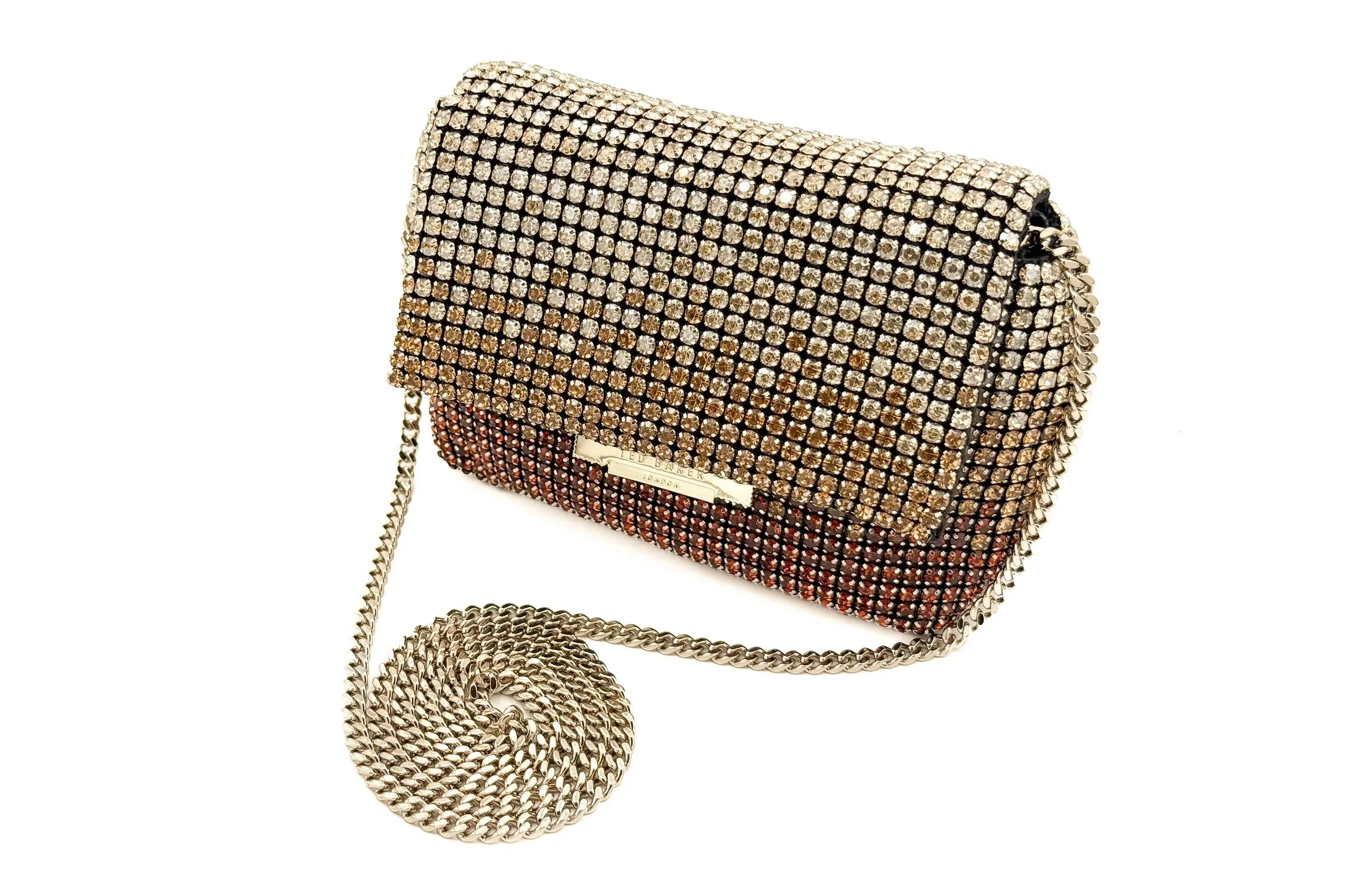 A rectangular clutch purse covered in brass-colored rhinestones with a metallic chain strap, isolated on a white background.