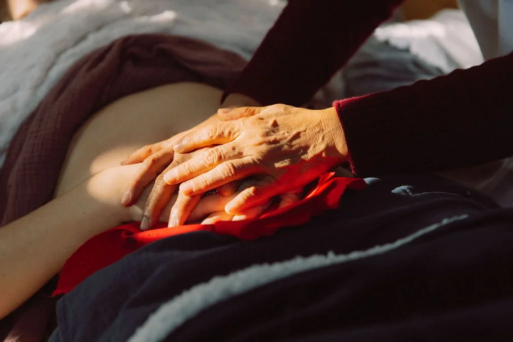 Hands on womb in a closing of the bones ceremony after birth.