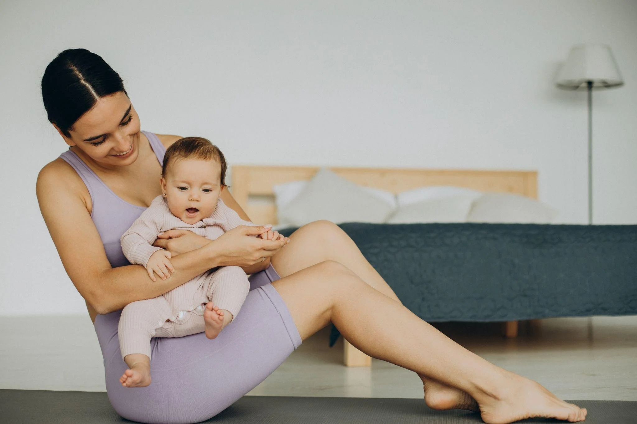 A mother in yoga clothes holding her baby smiling