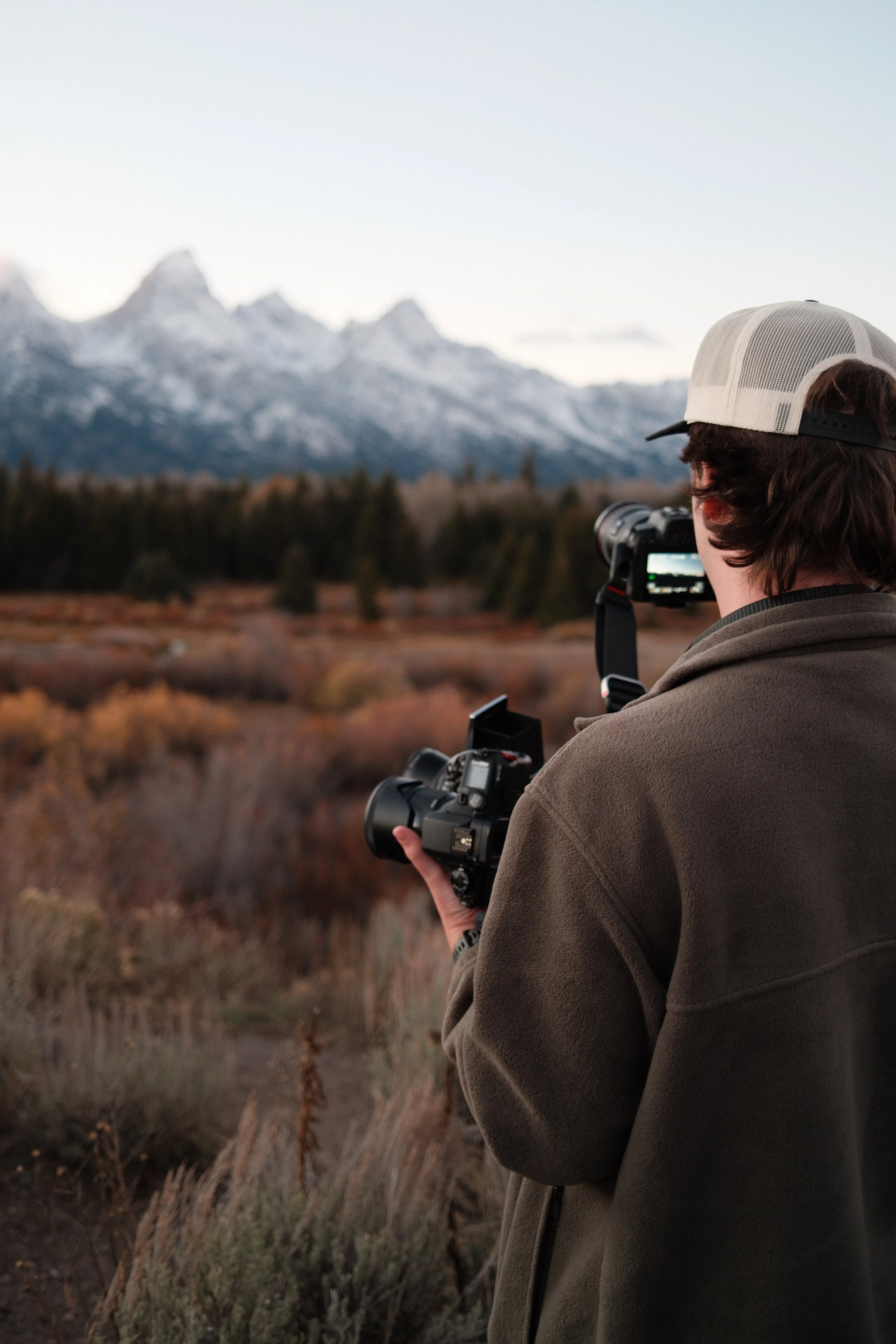 Joey Trcka intimate wedding photographer holding multiple cameras in Grand Teton National Park in Jackson Hole, Wyoming.