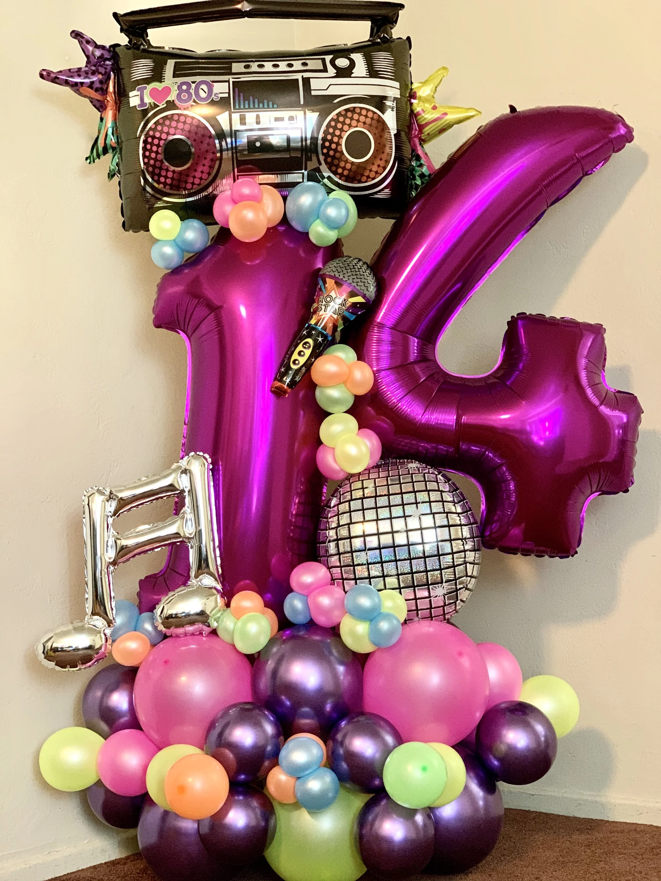 Colorful balloon arrangement with number 14, boombox, and music theme including microphone and disco ball.