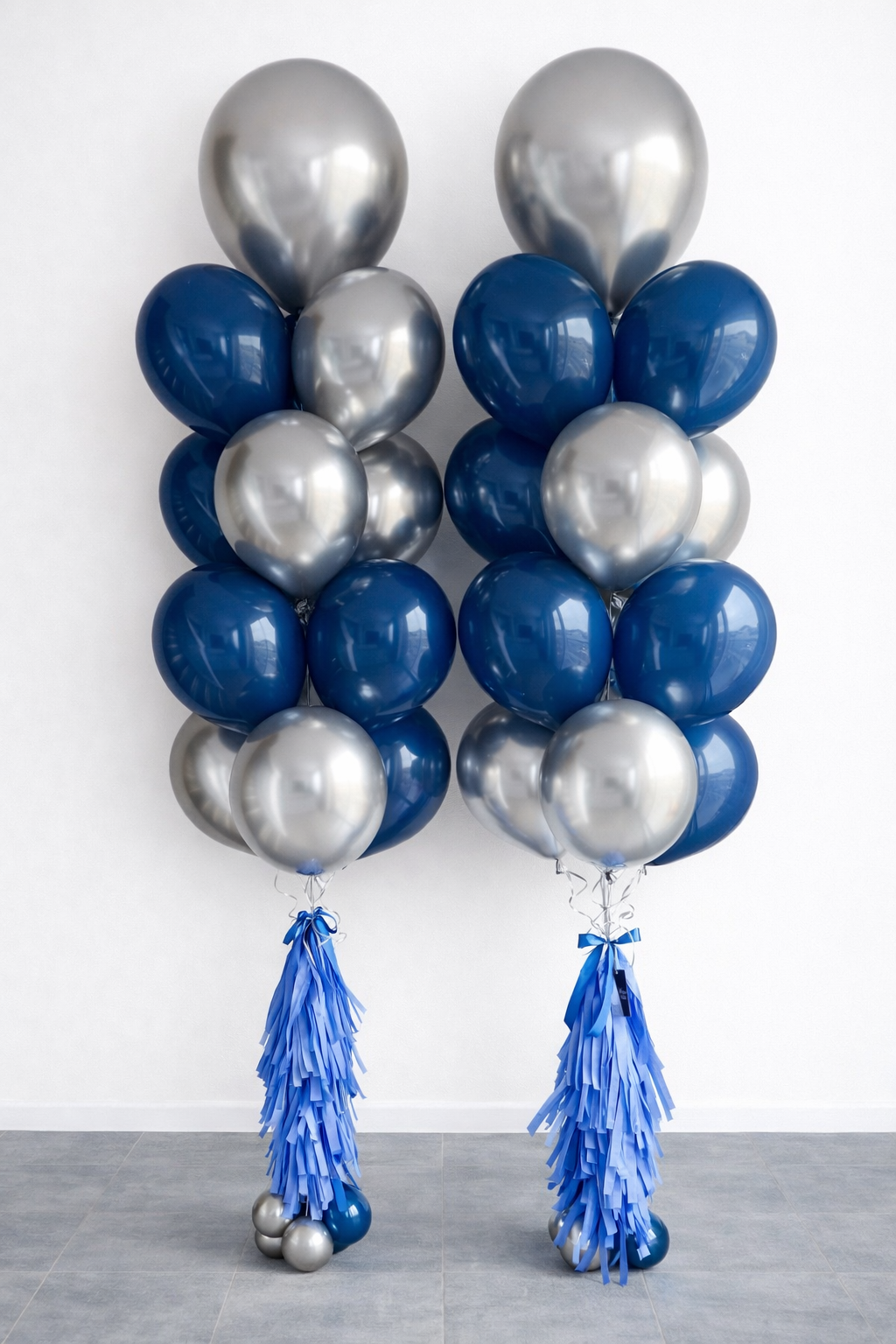Balloon columns with silver and blue balloons and blue paper tassels at the base.