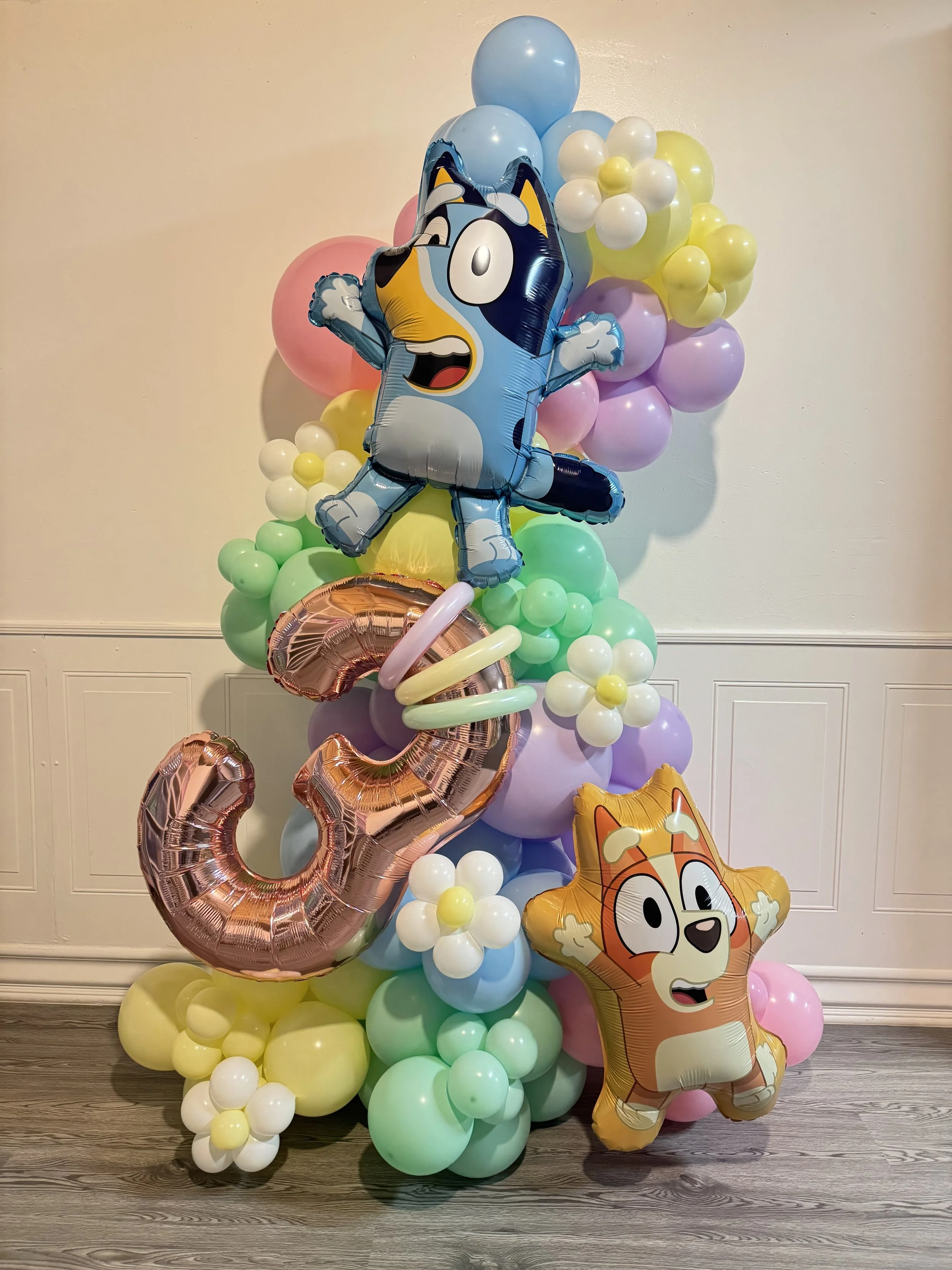 Balloon decoration featuring a large cartoon dog and cat character balloons, colorful round balloons, and metallic number 2 and 3 balloons.