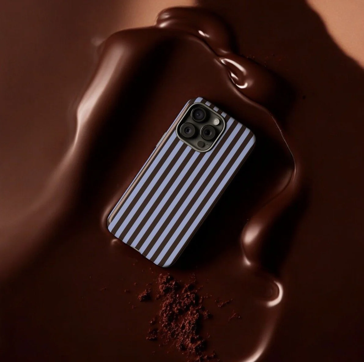 Smartphone with black and white striped case resting on melted chocolate with chocolate powder.