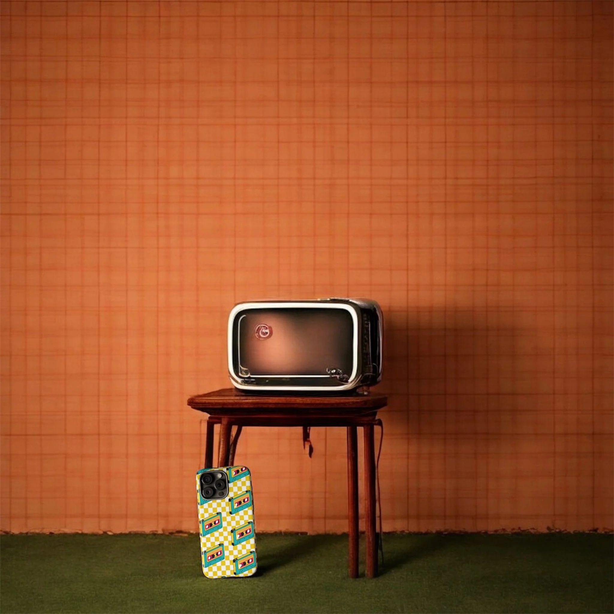 An old portable TV on a small wooden table and a smartphone with a retro cassette tape design case, all set against a textured orange background with a green carpeted floor.
