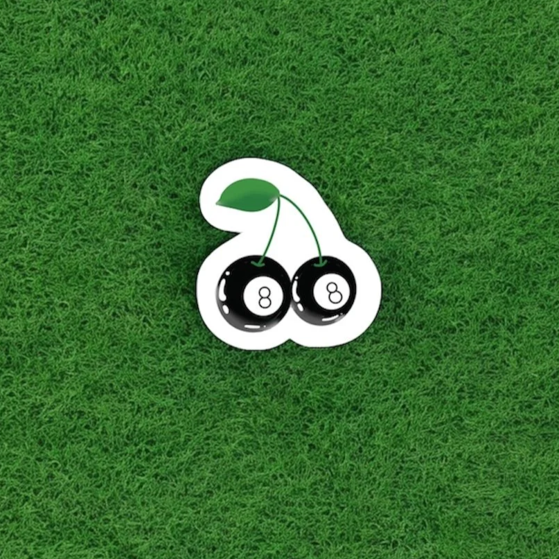 Sticker of two cherries edited to look like 8-ball pool balls, on a green grass background.