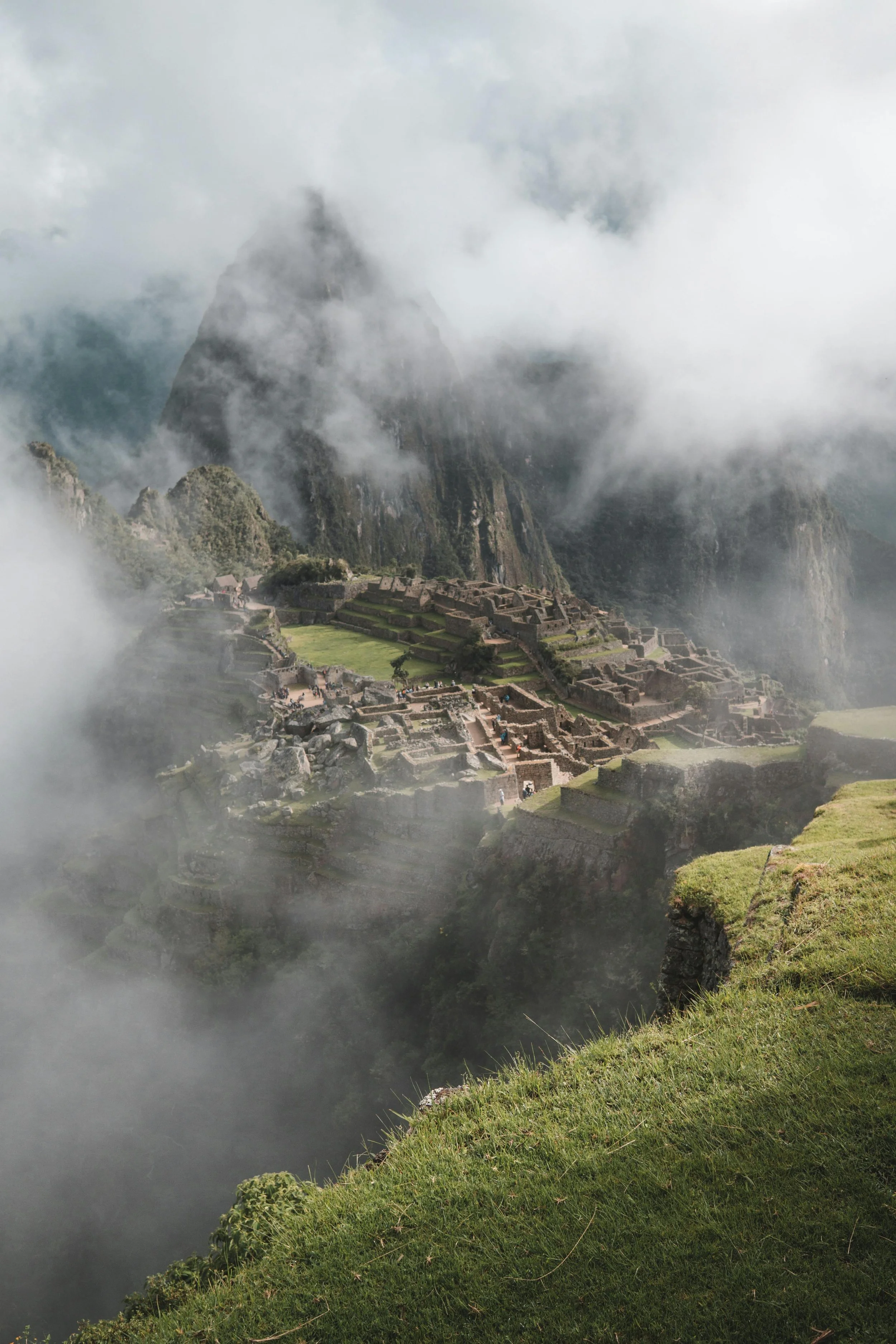 In den Wolken versteckt liegt die antike Inka-Stadt Machu Picchu in den Anden Perus, umgeben von grünen Hügeln und Berggipfeln.