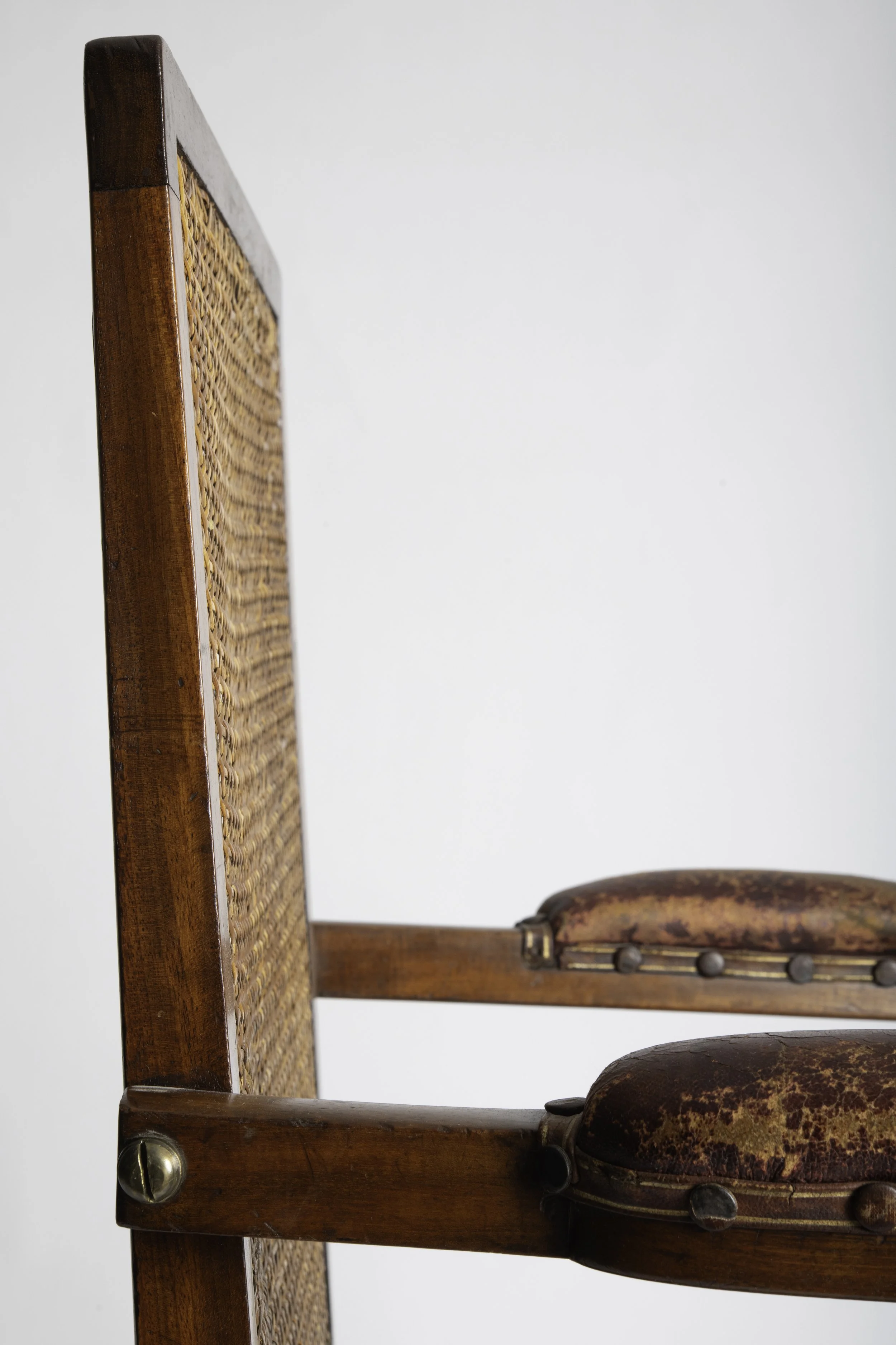 Side detail of the caned back, leather arm pads and brass pivot