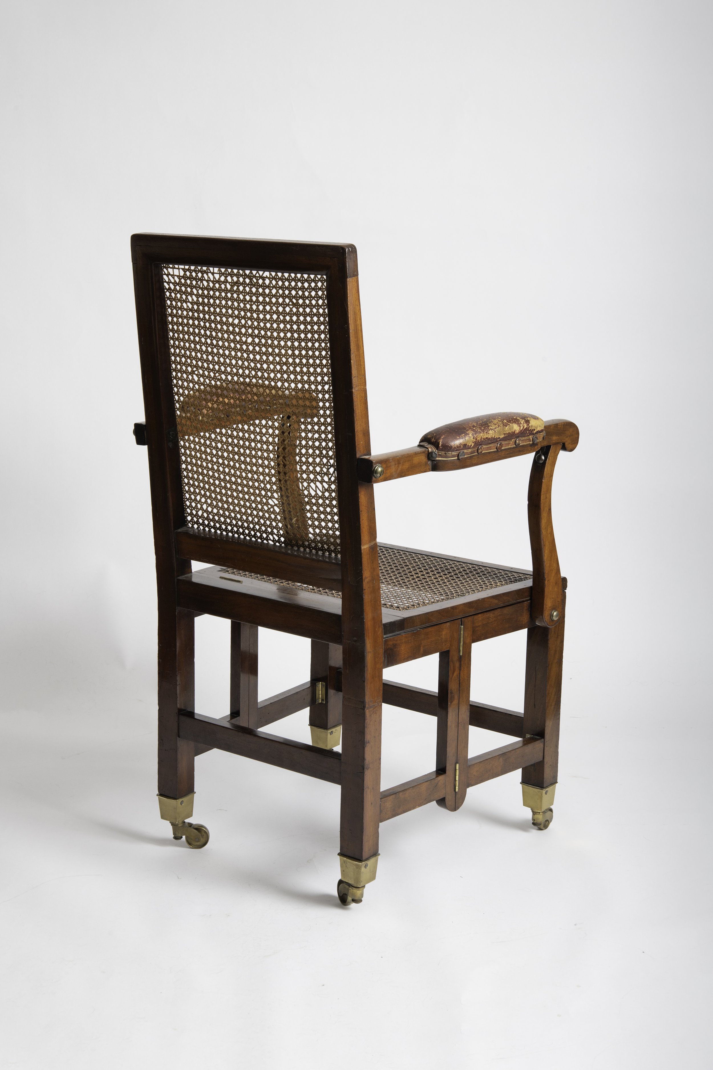 Rear three-quarter view showing the caned back and folding mahogany frame
