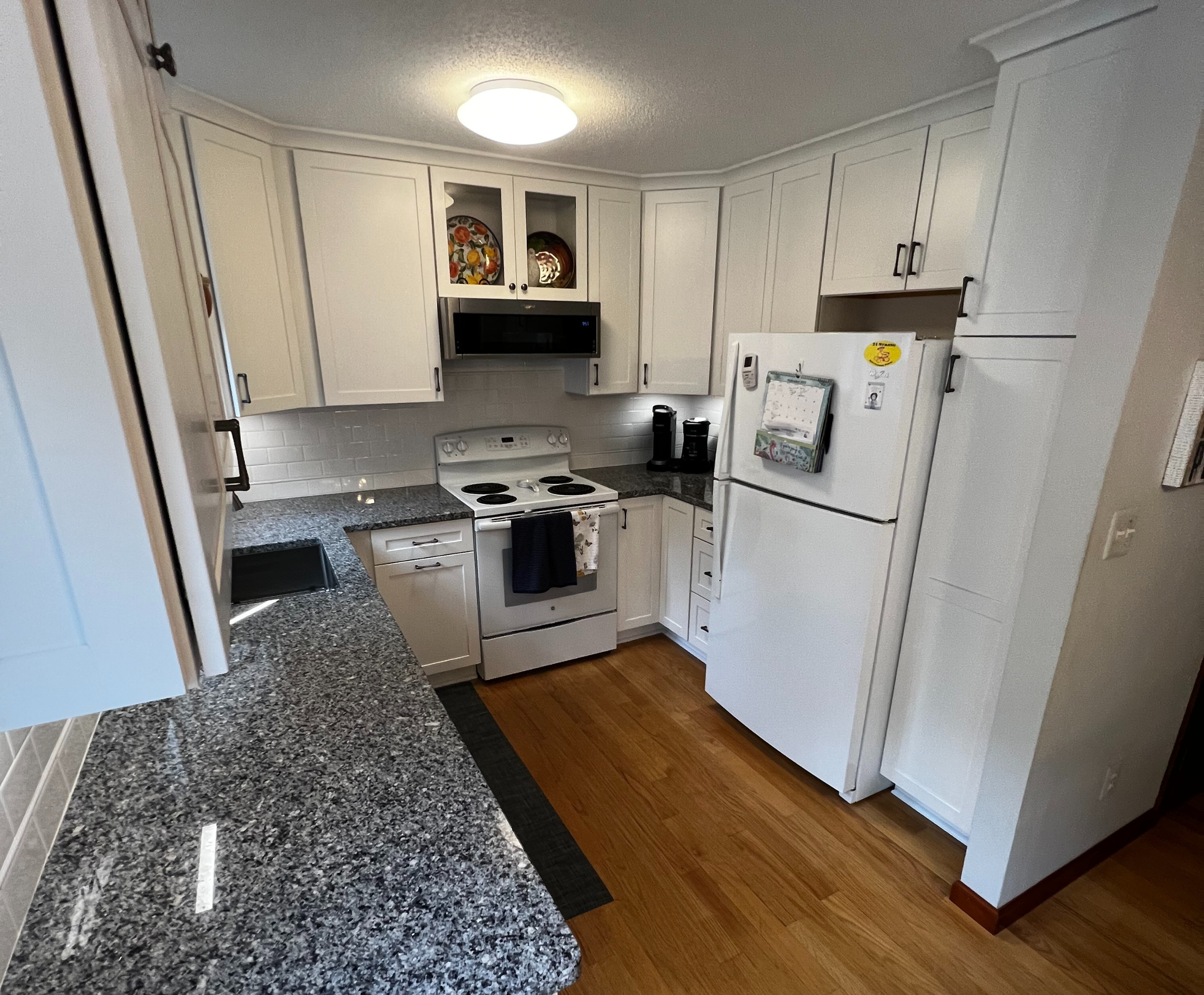 An after photo of a Glen Holman Contracting kitchen remodel with white cabinets and a tiled backsplash.