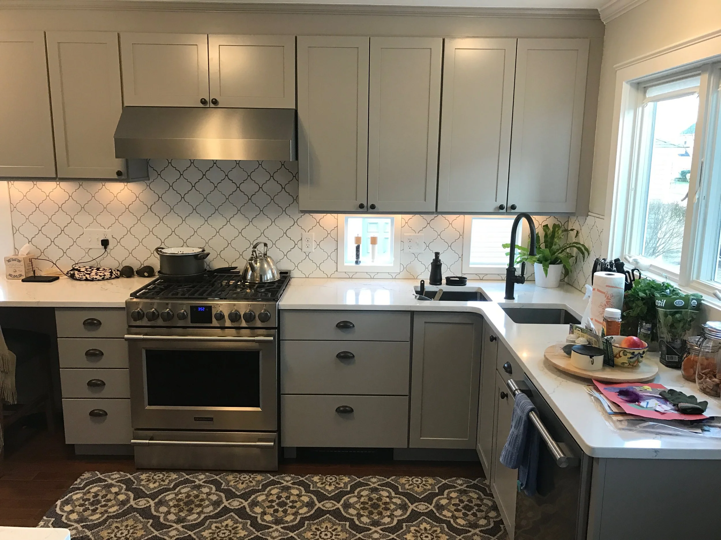 An after photo of a Glen Holman Contracting kitchen remodel with gray cabinets and a tiled backsplash.