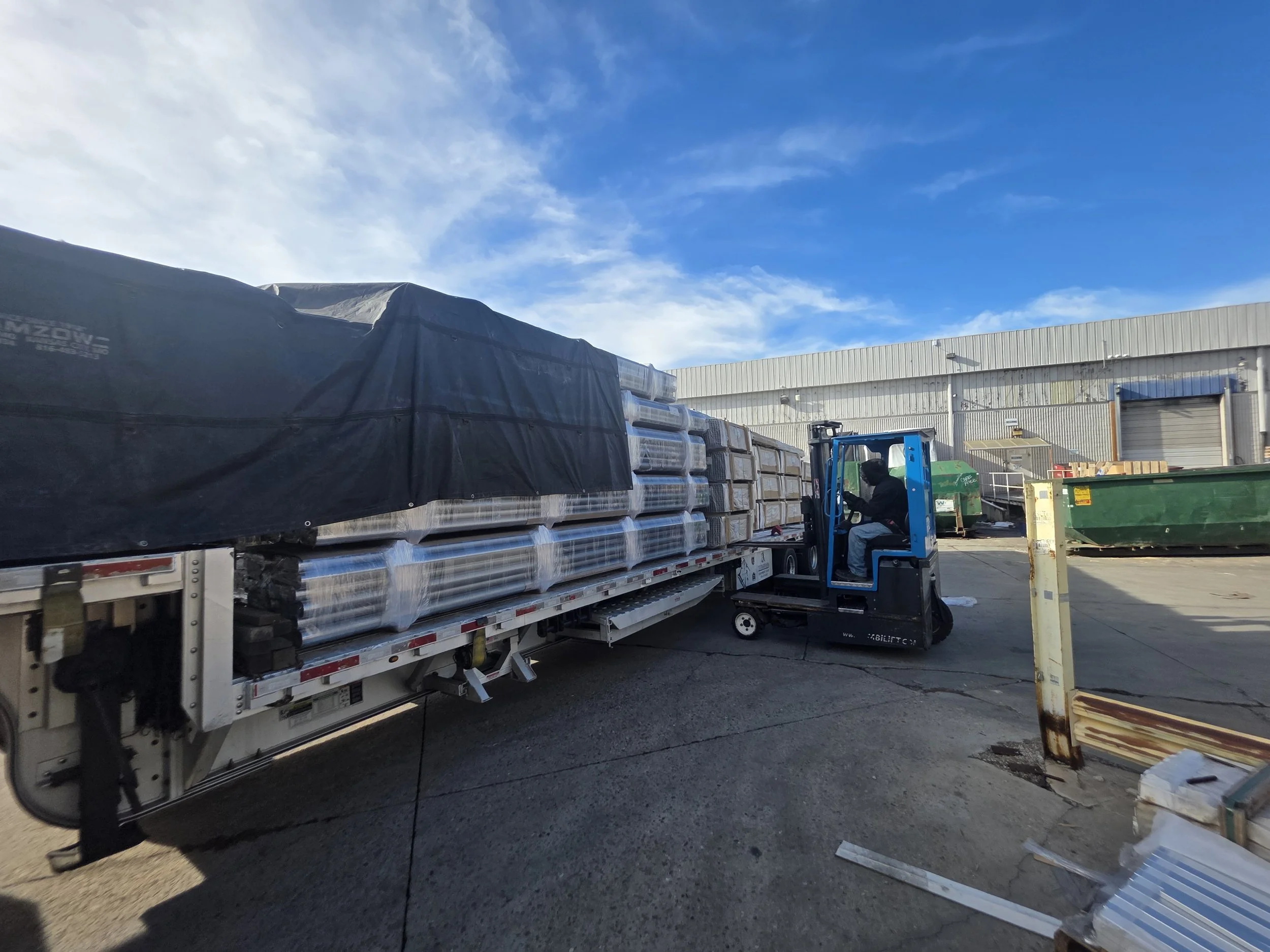 Three refrigerated semi-truck trailers parked in a lot during sunset, with a cloudy sky overhead.