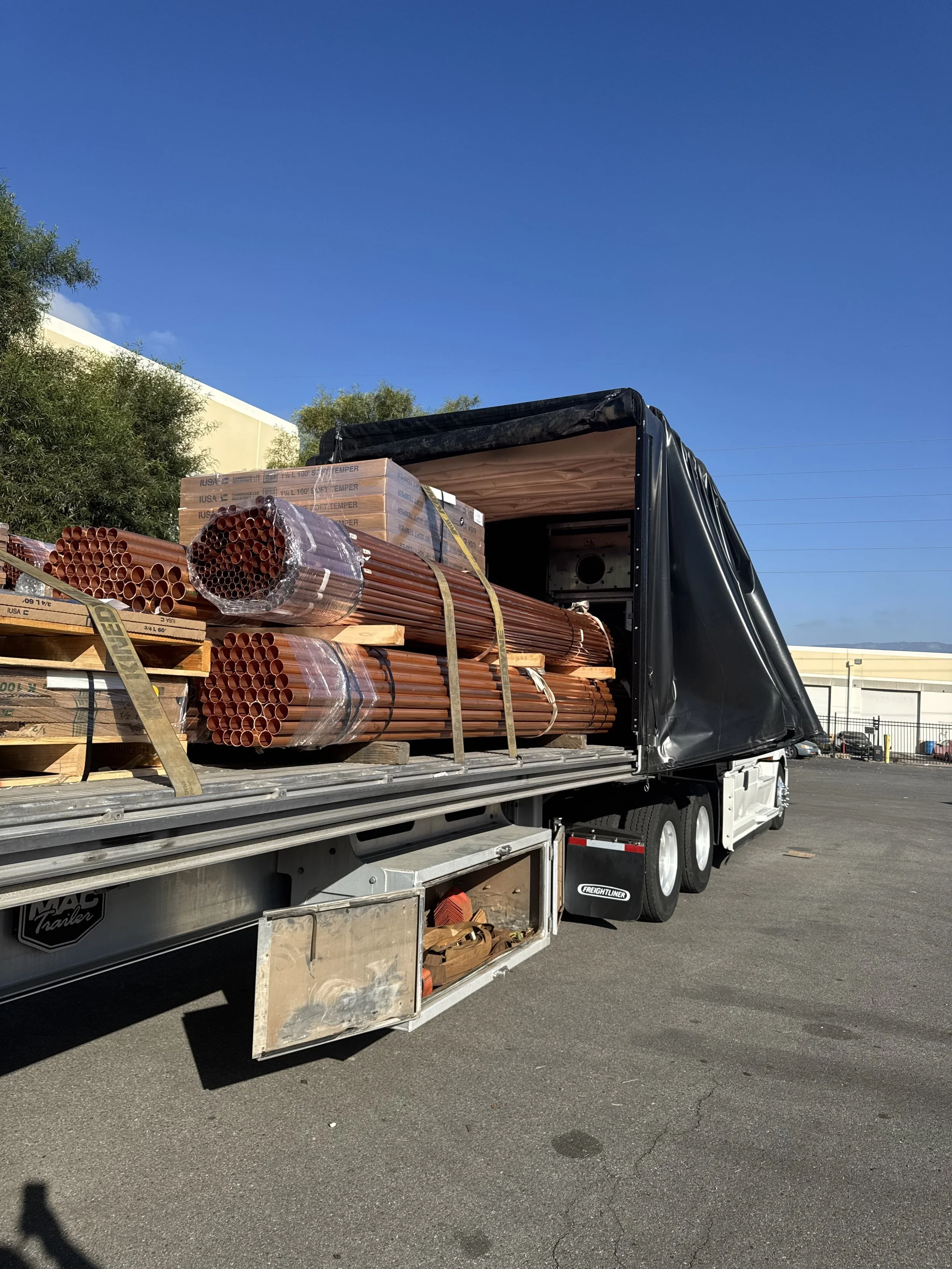Three refrigerated semi-truck trailers parked in a lot during sunset, with a cloudy sky overhead.