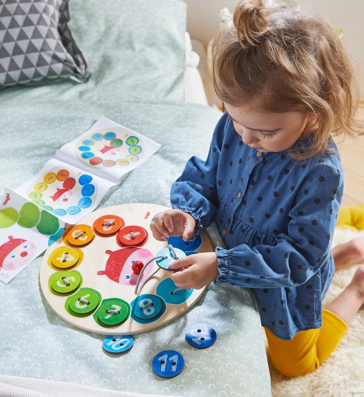 Photo of a girl threading string through a wooden and felt threading toy in the image of a caterpillar