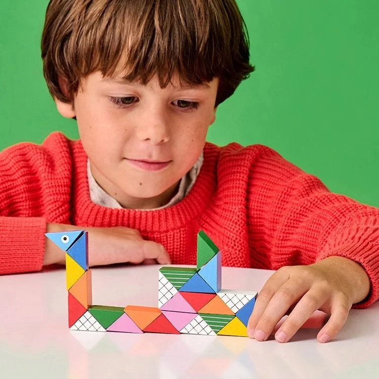 Image of a boy in a red sweater playing with a wooden twist block toy in the shape of a snake