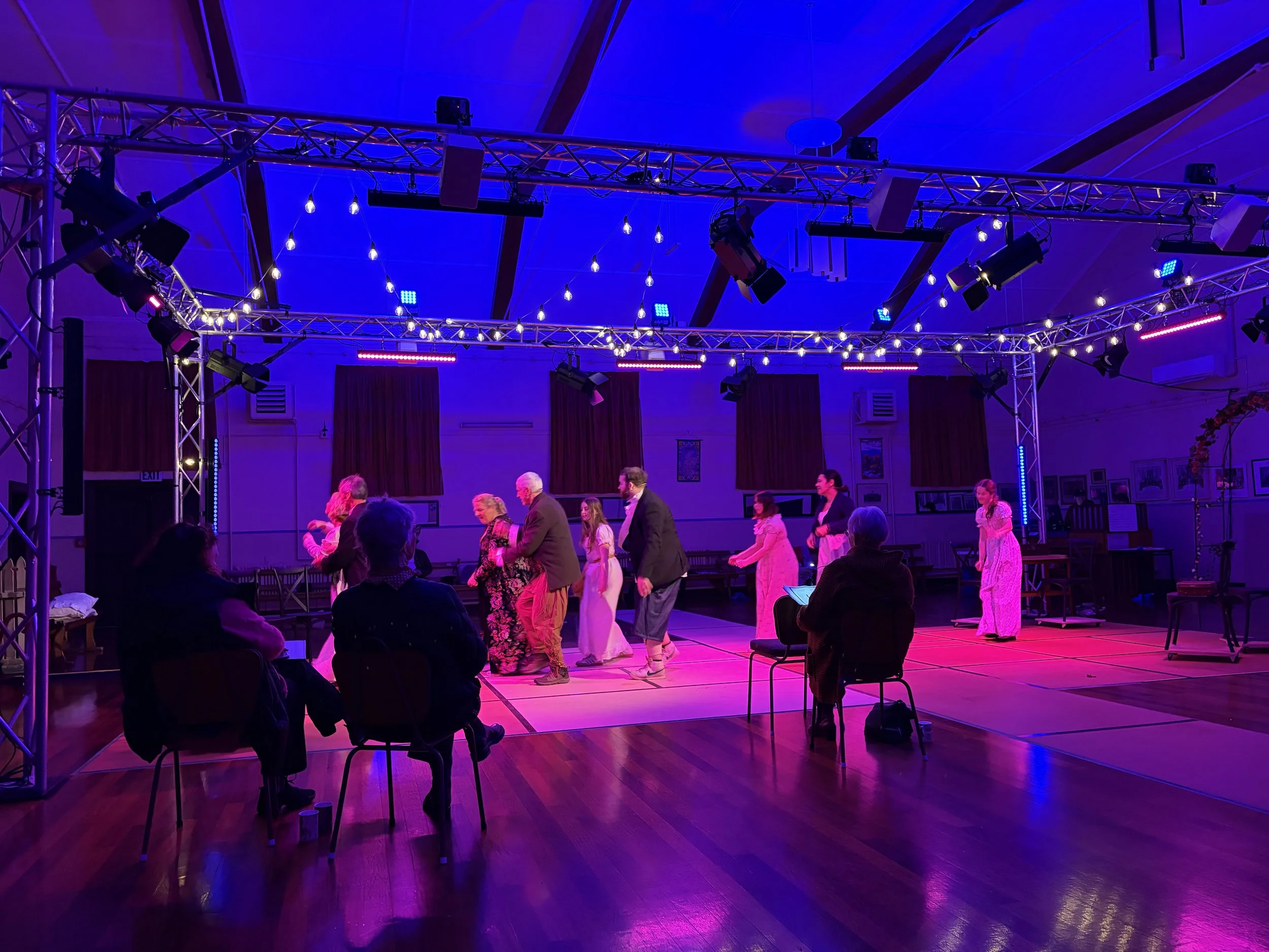 People dancing on a stage decorated with lights in a large indoor venue.