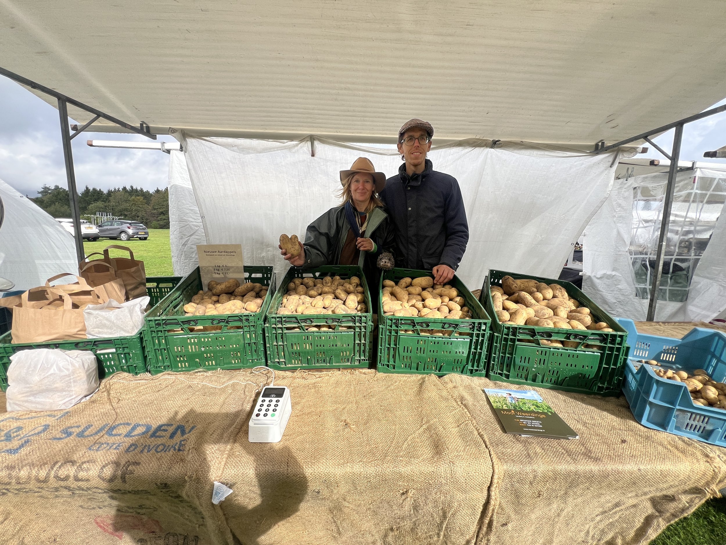 In de stromende regen aardappels verkopen op de markt in Klijndijk 