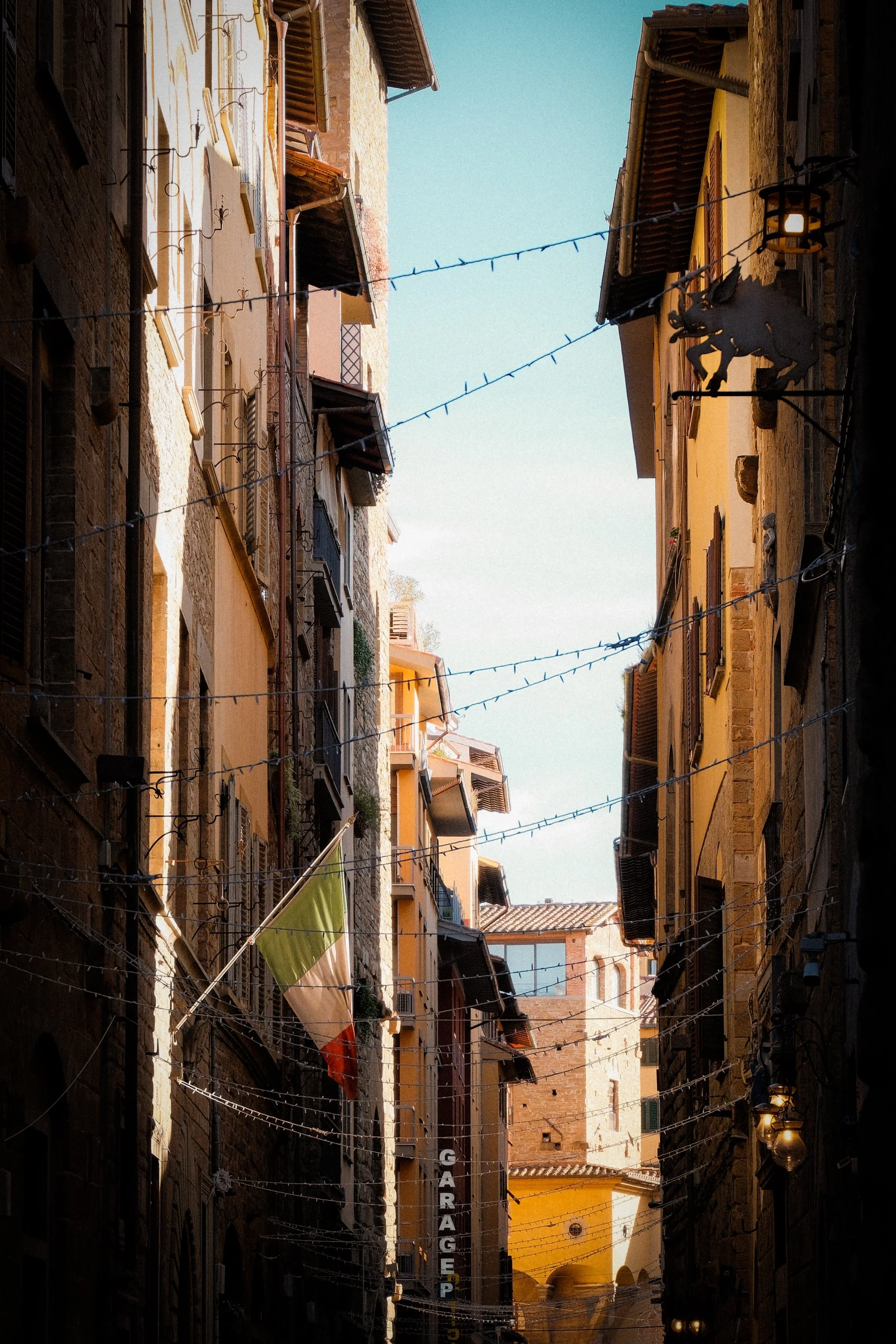 Narrow historic street with warm sunlight and old buildings in Florence, Italy
