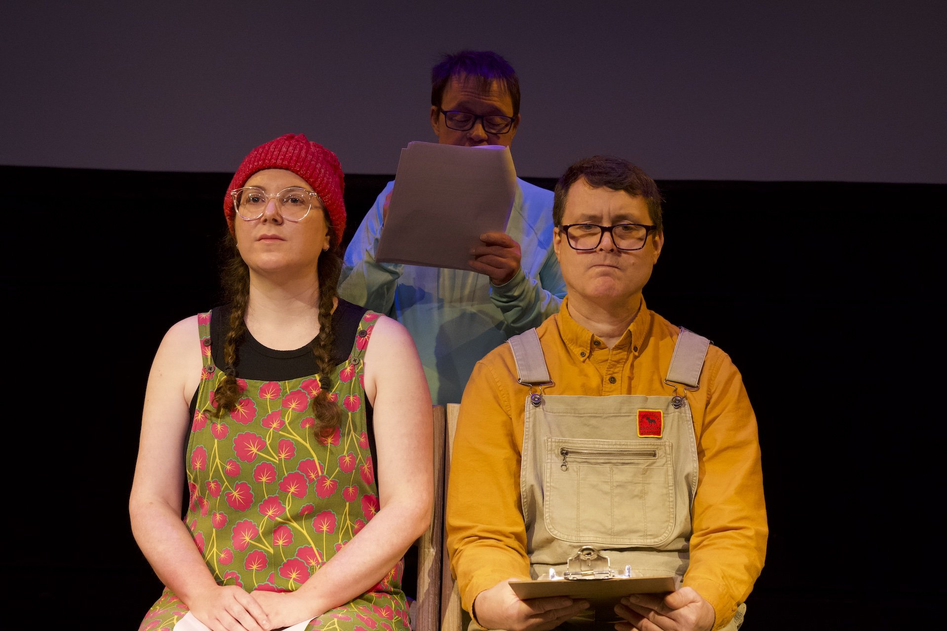 Photo by Tyler Preece. Clockwise from left, Zoe Tomaras, Andreas Prinz and Timothy Anderson. Zoe and Timothy sit on chairs side by side, facing the audience. Andreas stands behind them, reading from his script.