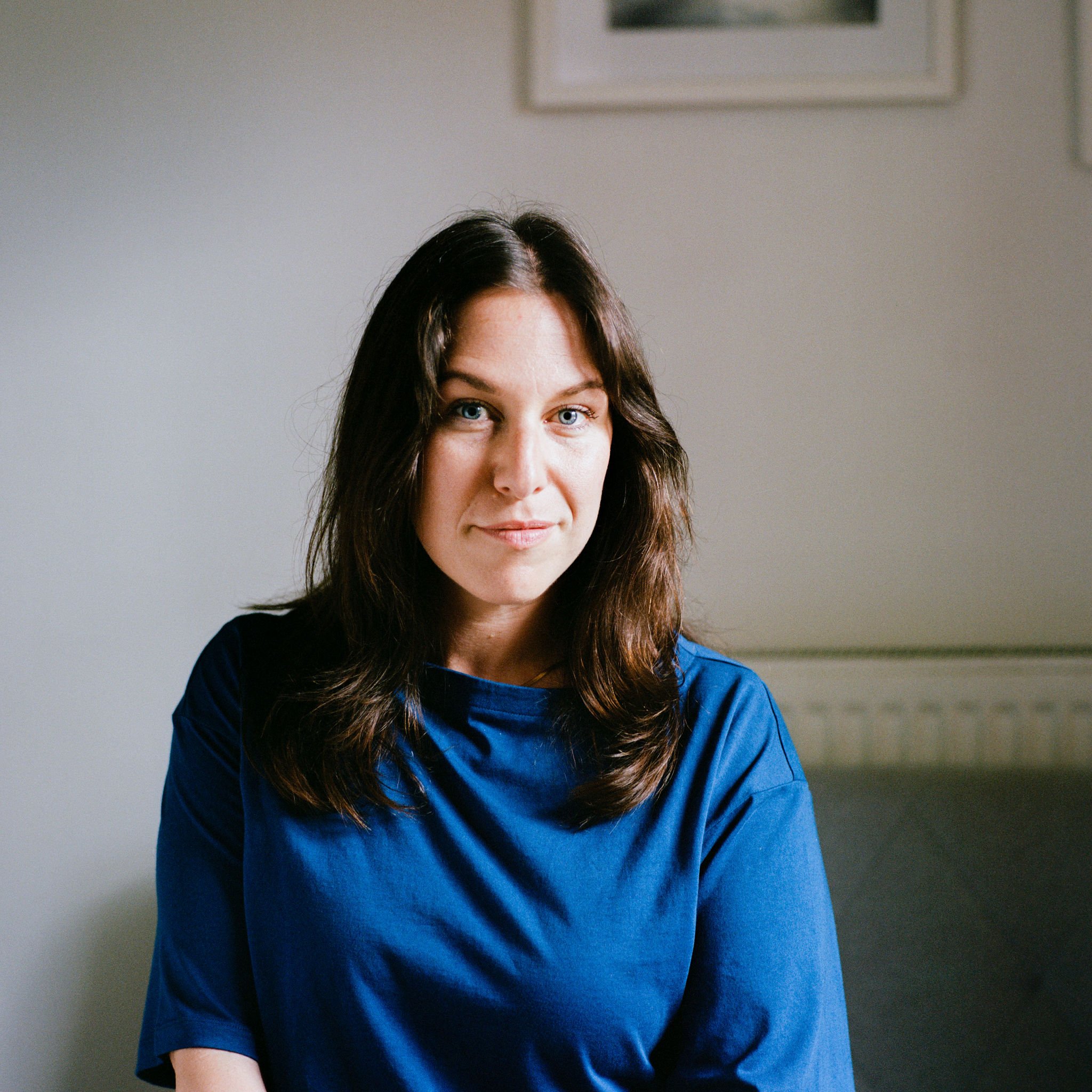 Sasha is a white woman with dark medium length hair, wearing a blue shirt.