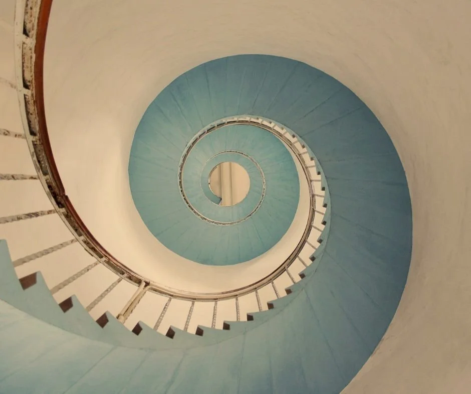Spiral staircase view from below showing the handrails and steps curving upward.
