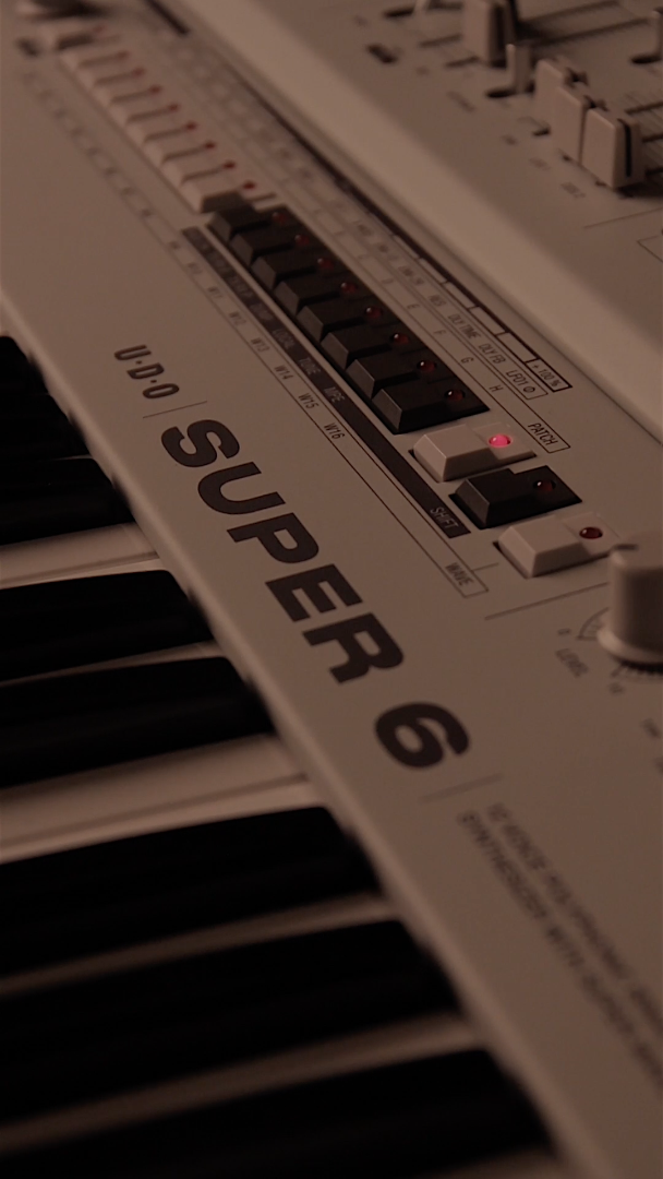 Close-up of the UDO Super 6 synthesizer keyboard with black and white keys and control buttons.