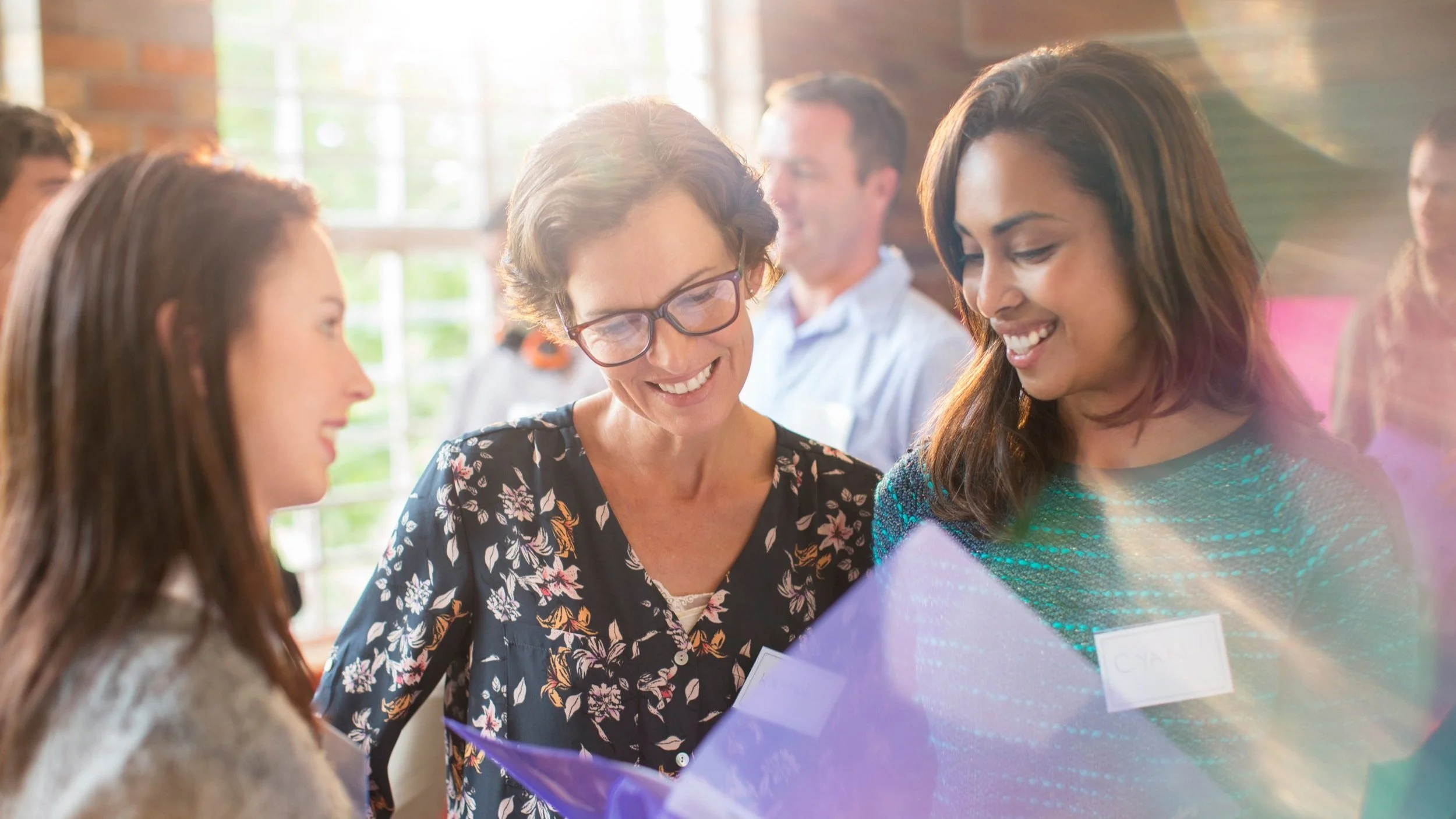 Realtors® reviewing marketing materials together at a networking event, symbolizing relationship-building and targeted real estate marketing strategies