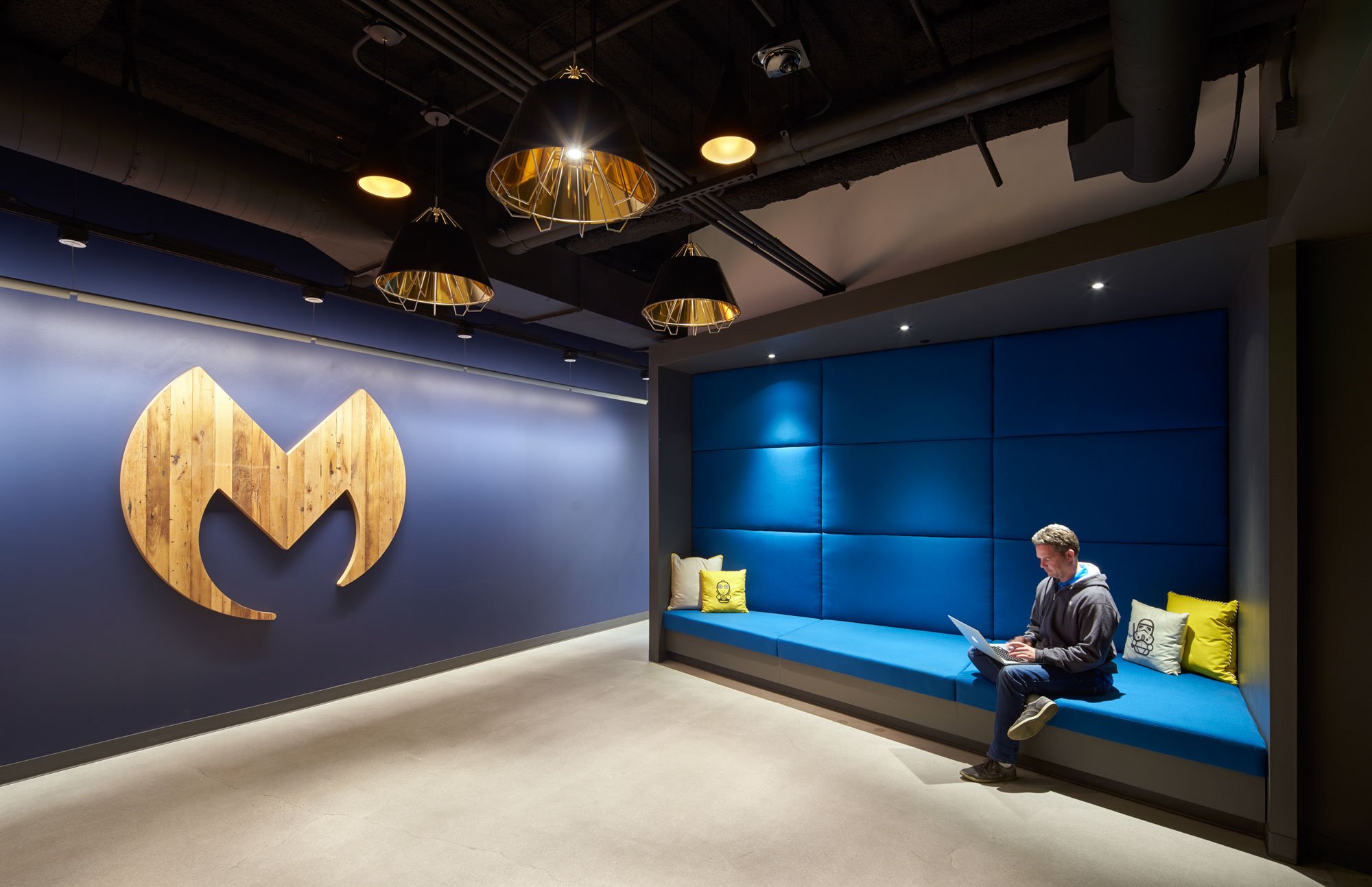 Bench seating and wall graphics on a blue wall in a modern office.