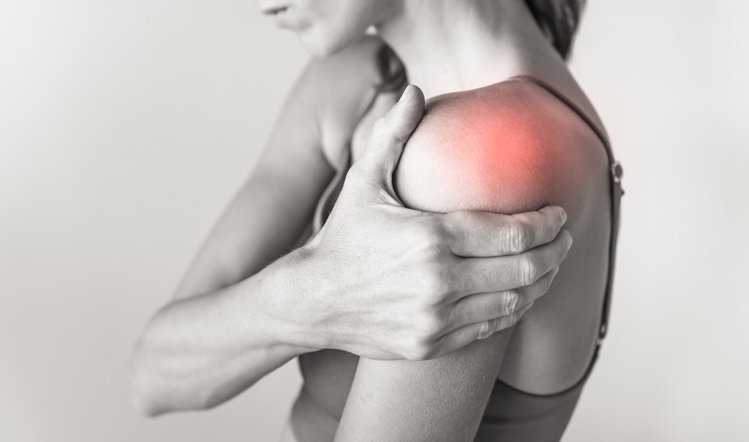 A woman showing her shoulder with a red, inflamed area indicating pain or injury.
