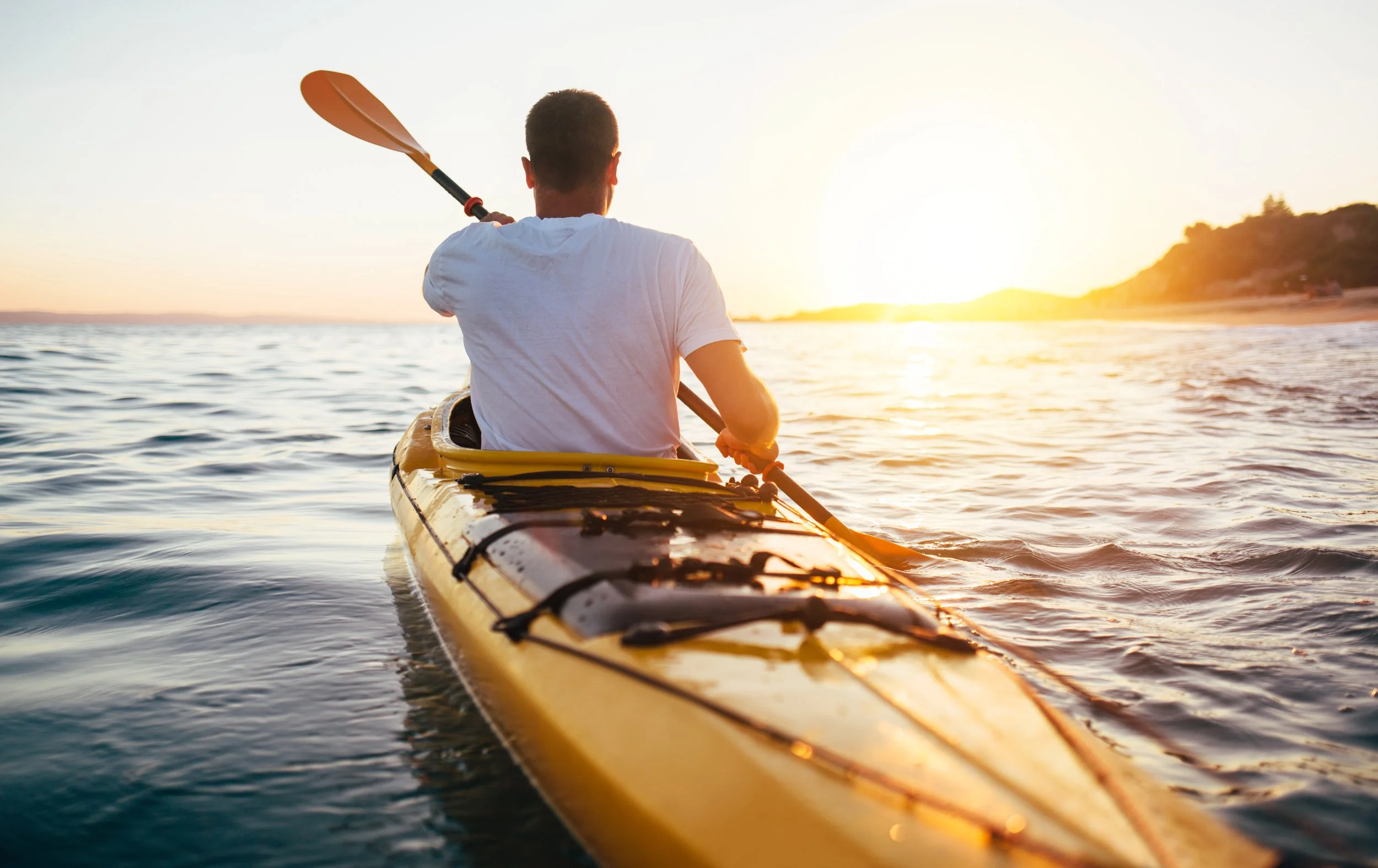 Man kayaking on the water during sunset