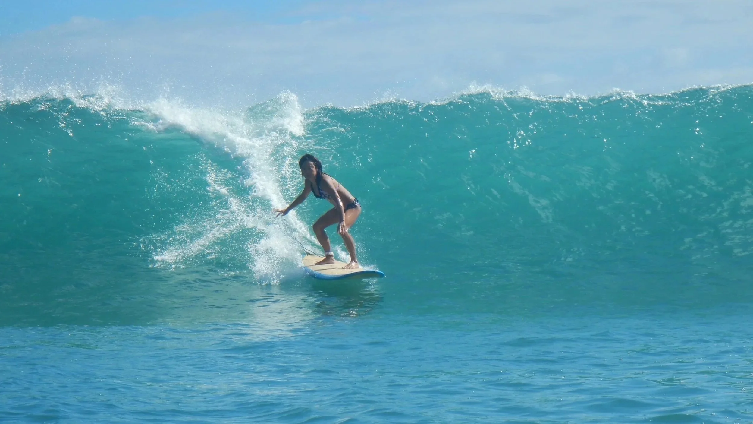 A Hook Up Surfing surf school surf coaching session client surfing on a large Waikiki ocean wave.