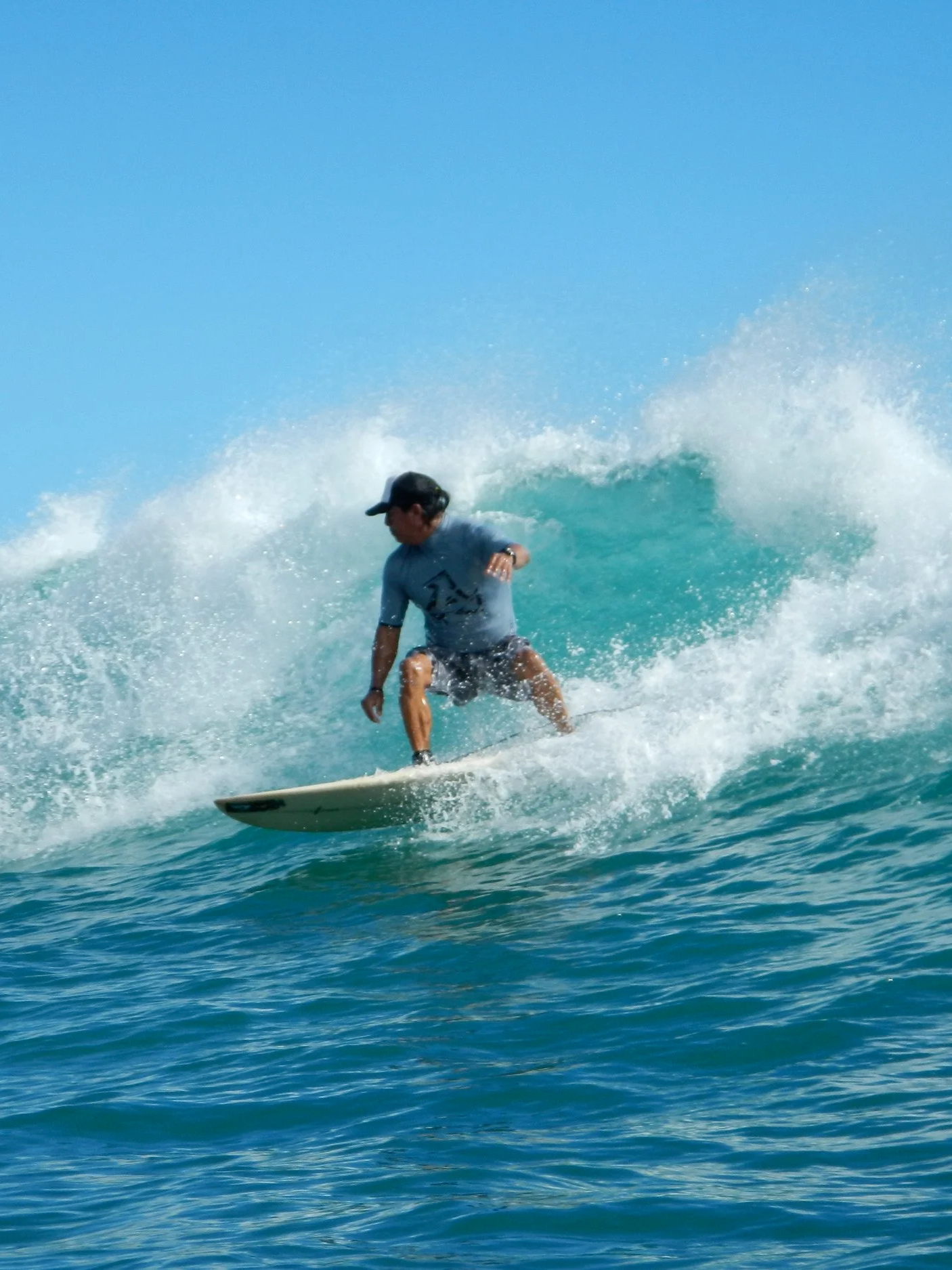 Ivan founder of Hook Up Surfing, surfing on a wave in the warm Hawaiian ocean.