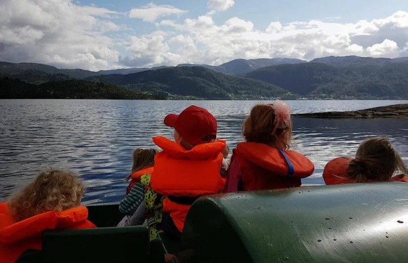 Barnehagebarn som nyter en sommerdag ved naustet ved fjorden