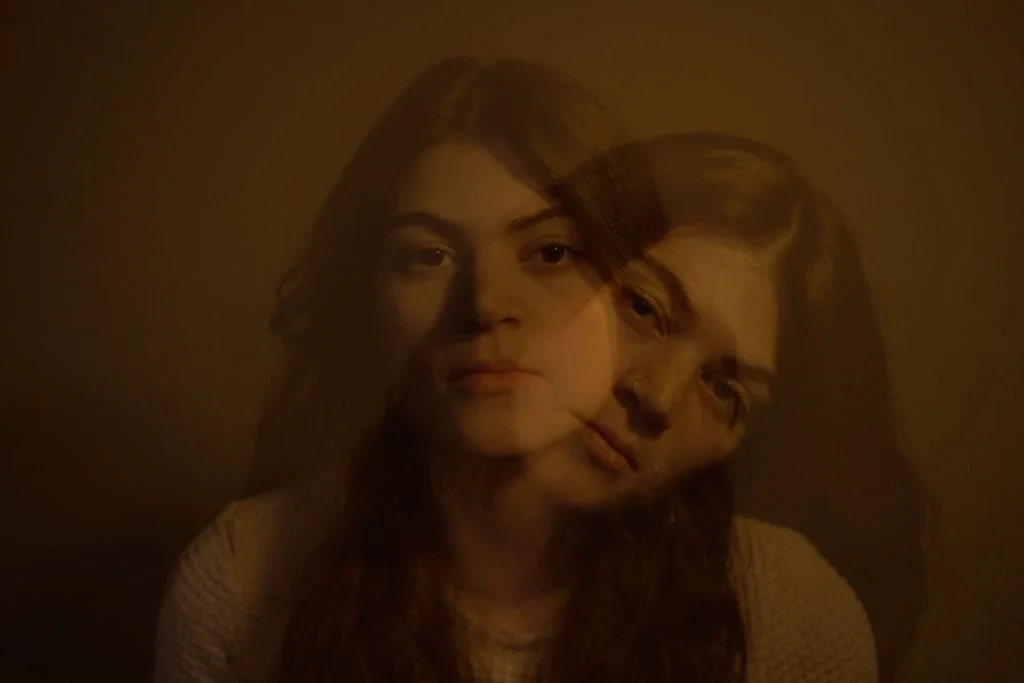 Overlapping images of Skye Darling, with double exposure appearing as two overlapping young women with long hair against a dark background.