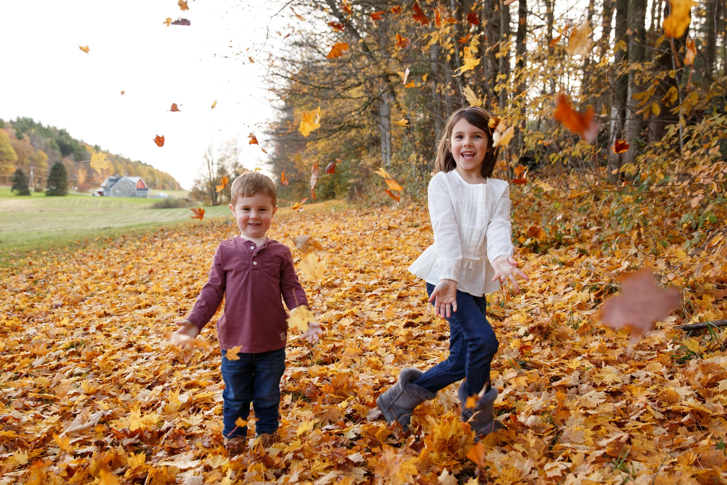 Two children playing in fall foliage in vermont 