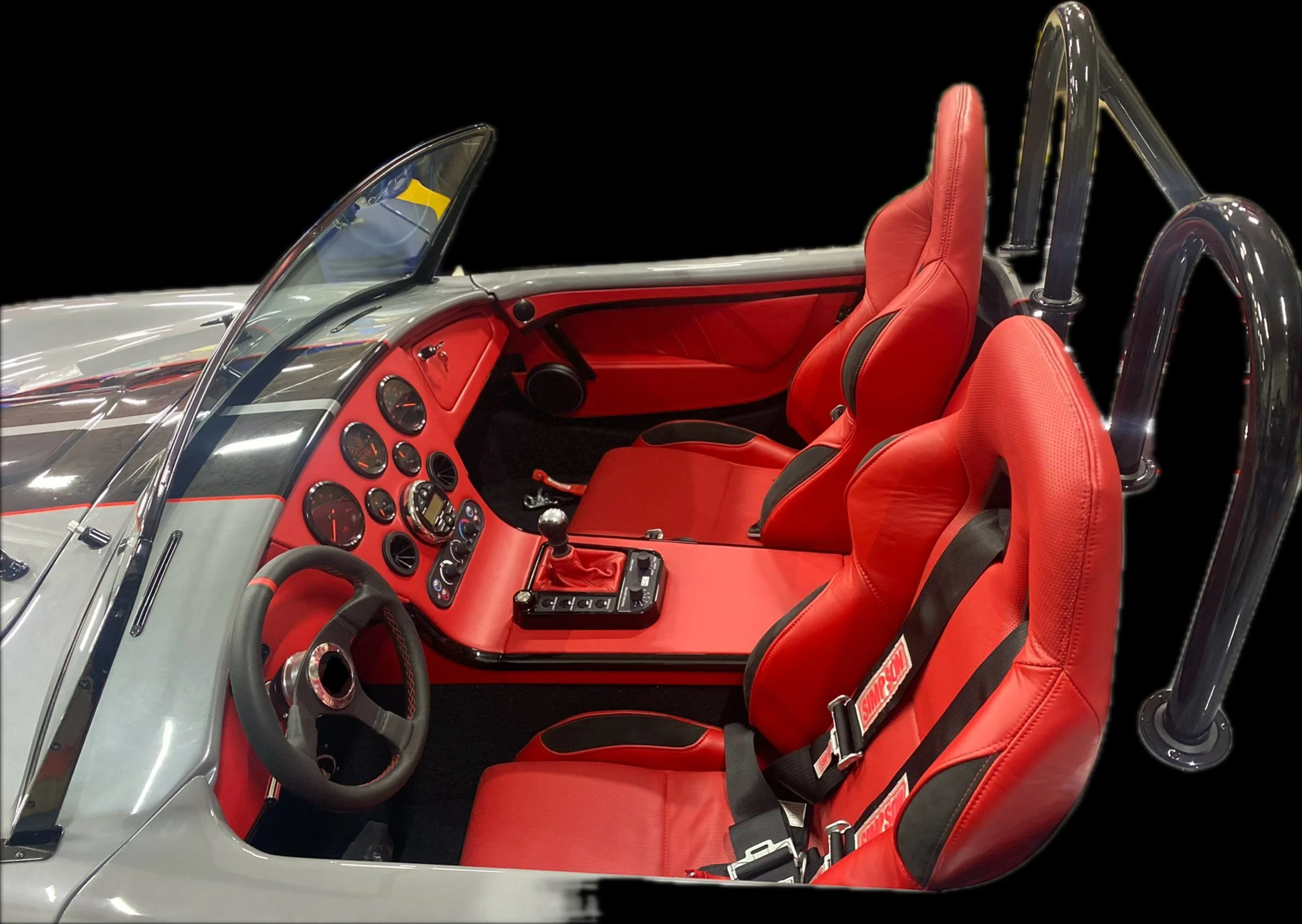 Interior of a race car with red seats, dashboard, and steering wheel, with a focus on the cockpit area.