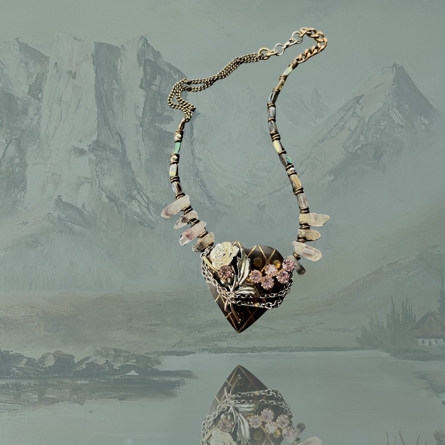 Ornate heart-shaped necklace with floral design against mountainous backdrop