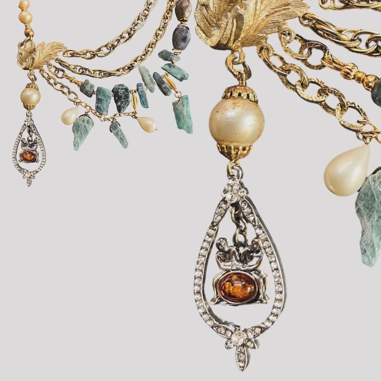 Close-up of an ornate multi-layered necklace with gold chains, turquoise stones, pearls, and decorative pendants.