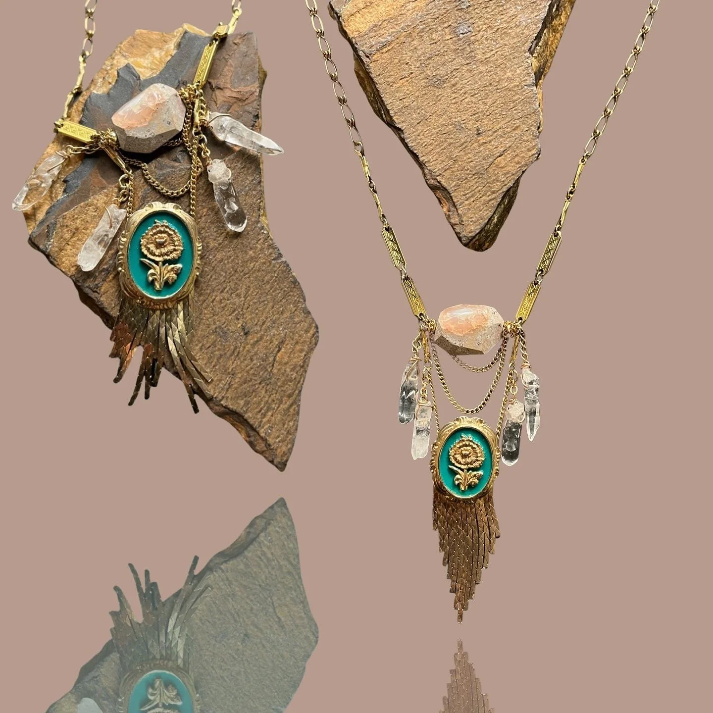 Handmade necklace with crystal pendants, teal and gold floral medallion, and chain tassels displayed on rock background.