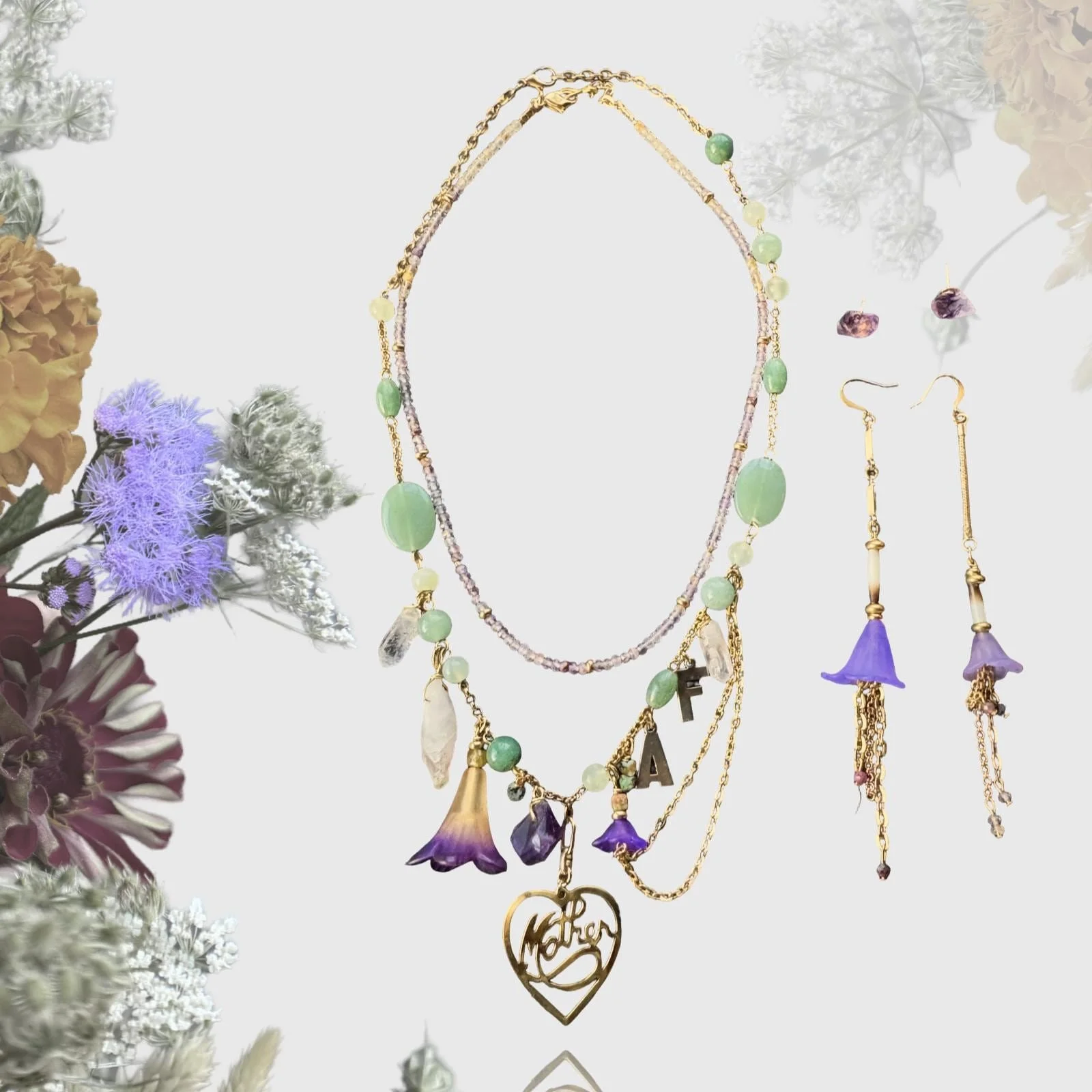 Gold and green necklace with floral and heart-shaped pendants, and matching earrings on floral background.