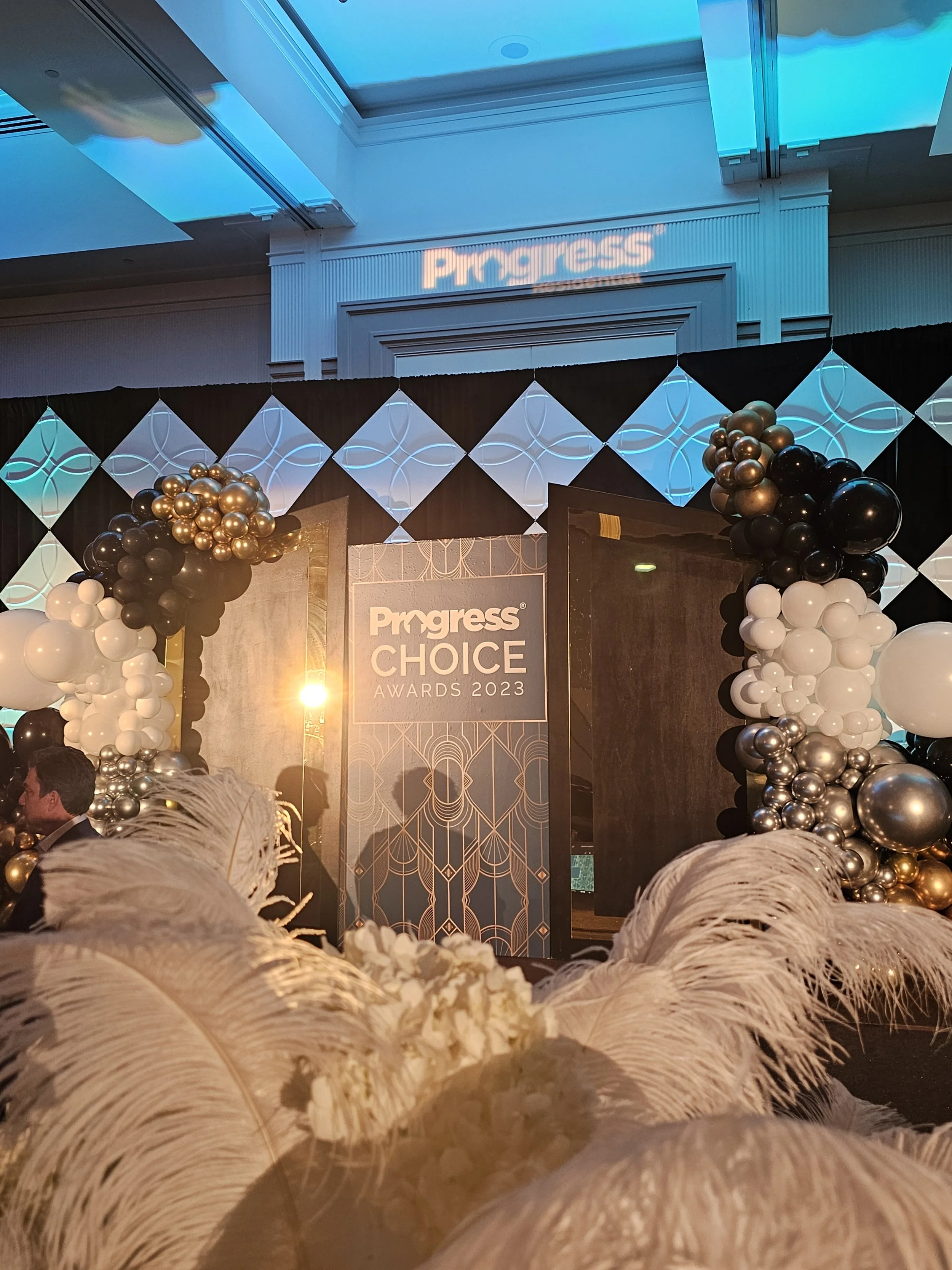 Entrance to the Progress Choice Awards 2023 event with balloon decorations, large feathers, and a decorative backdrop.